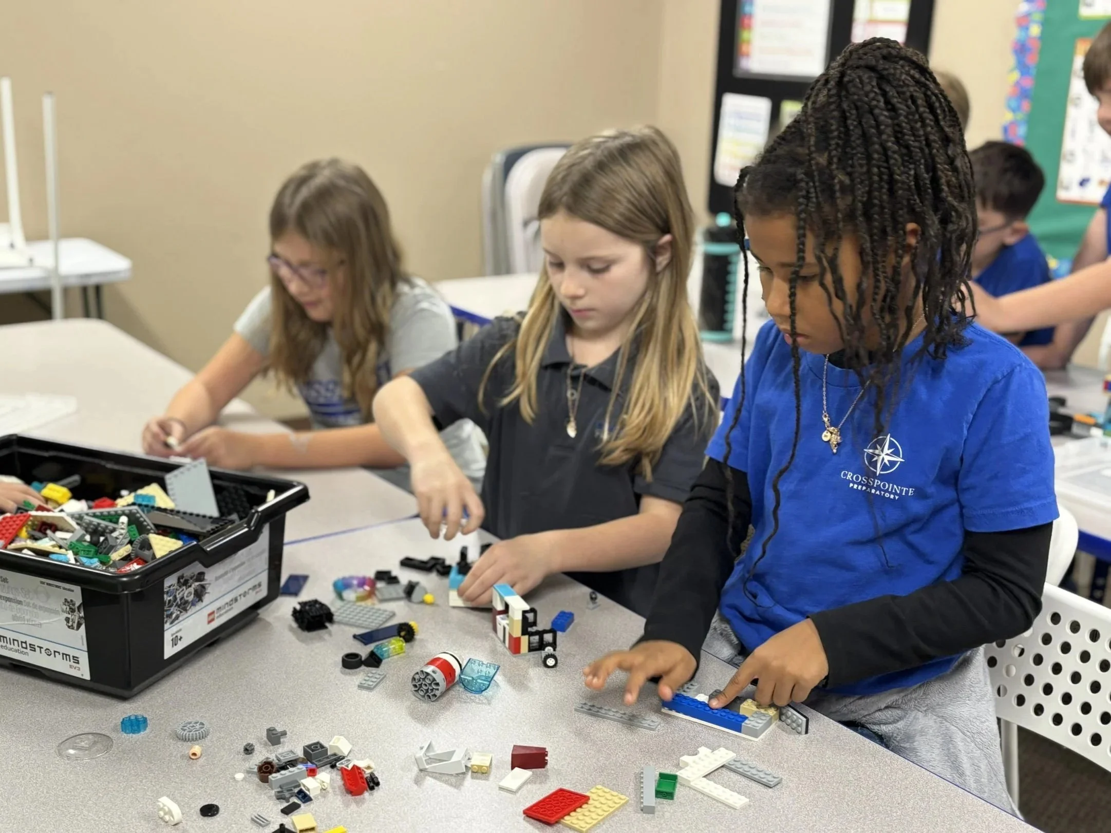 Children building with LEGO bricks at a classroom table.