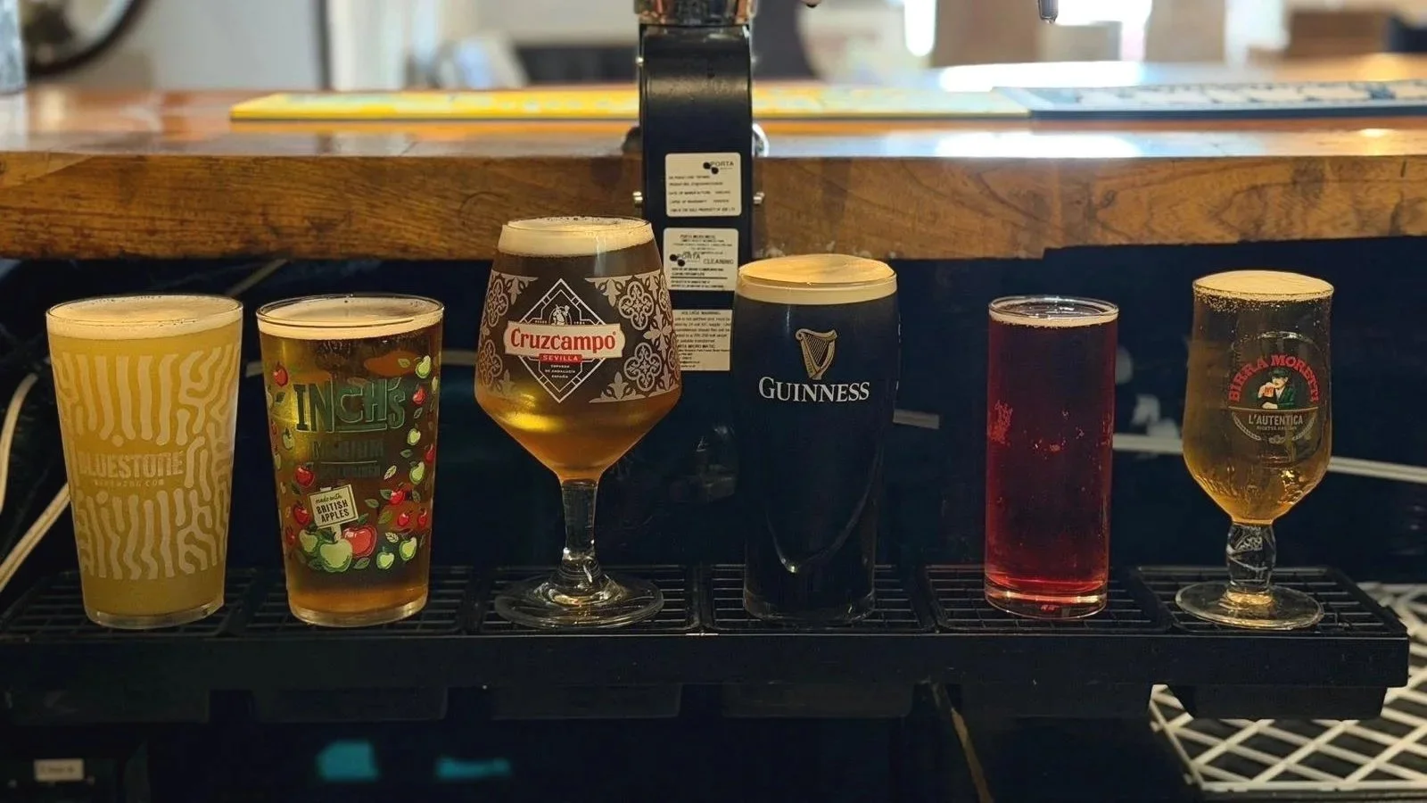 Six glasses of craft beer served on a black tasting tray at The Butchers Arms, a traditional country pub in Llanddarog, Carmarthenshire.