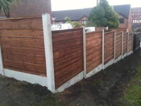 Wooden privacy fence with white concrete posts in a suburban yard.