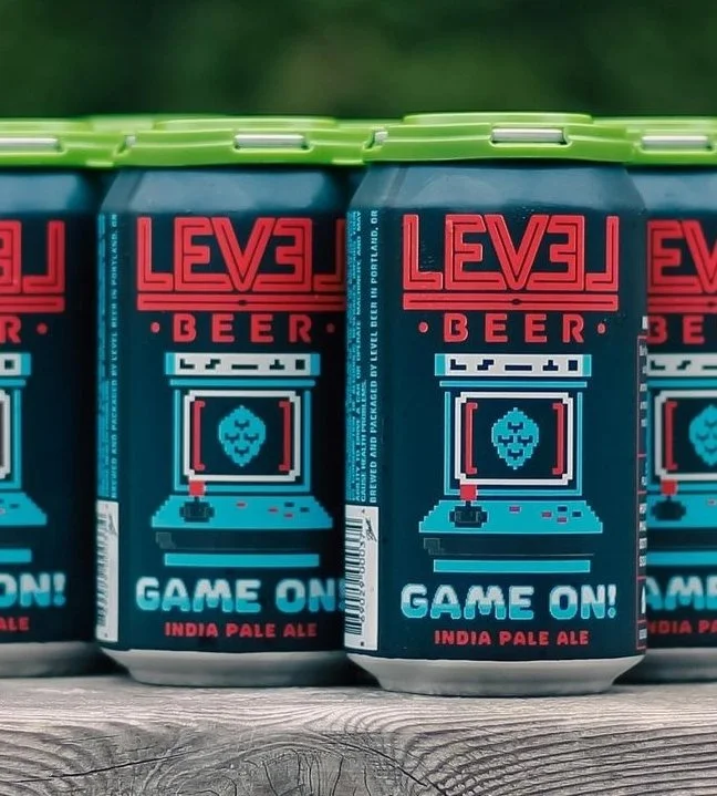 Cans of Level Beer "Game On!" India Pale Ale with retro arcade design.