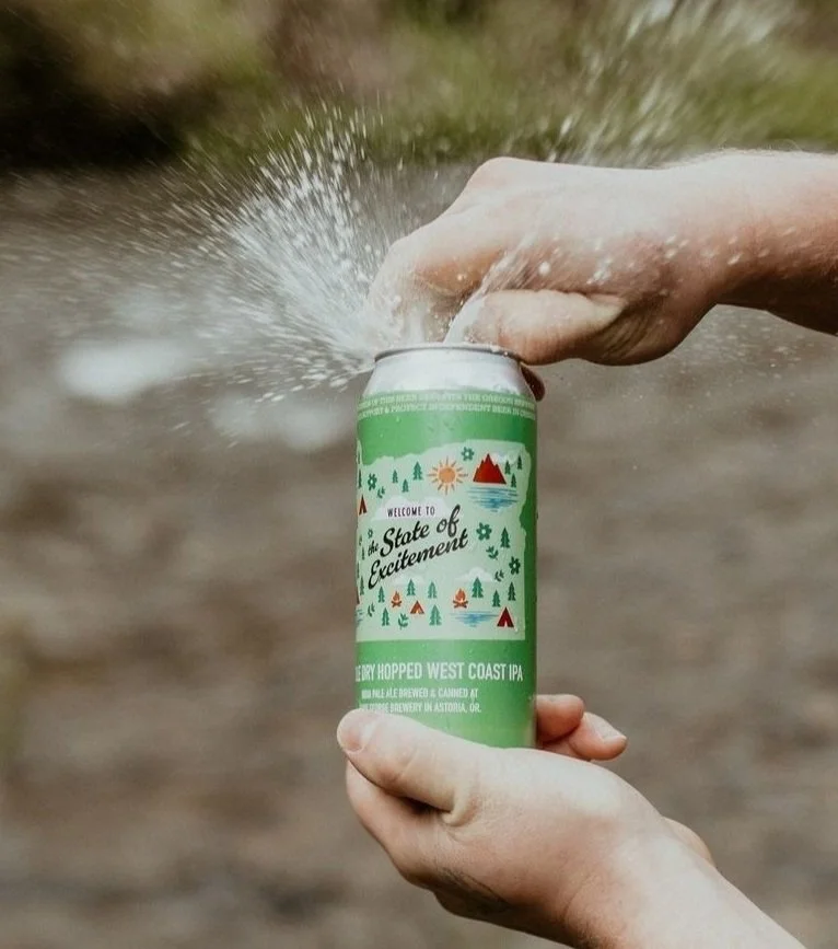 Person opening a can of "State of Excitement" craft beer, causing it to spray foam