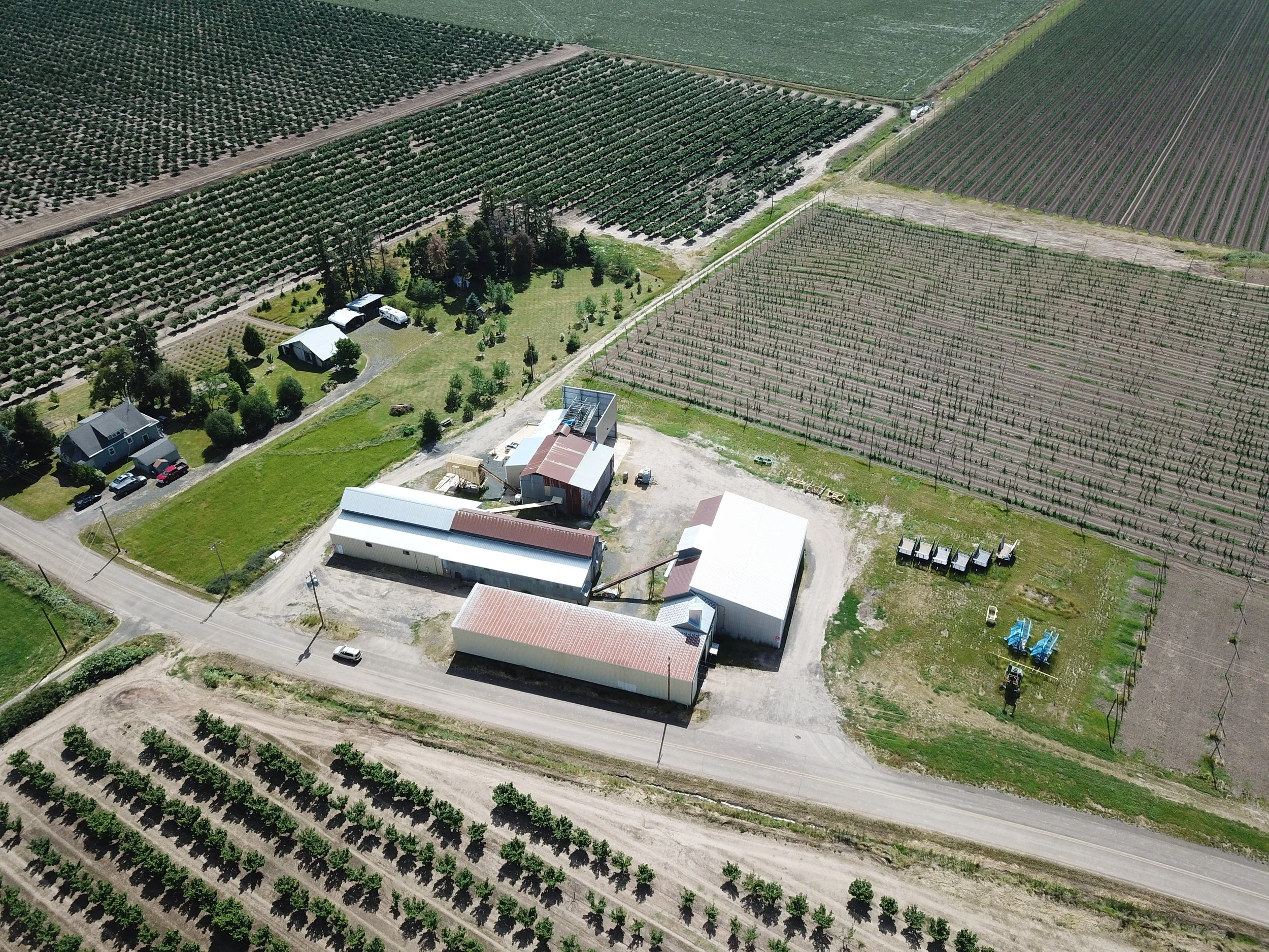 Aerial view of an orchard and farm with multiple buildings, trees, and fields for agriculture.