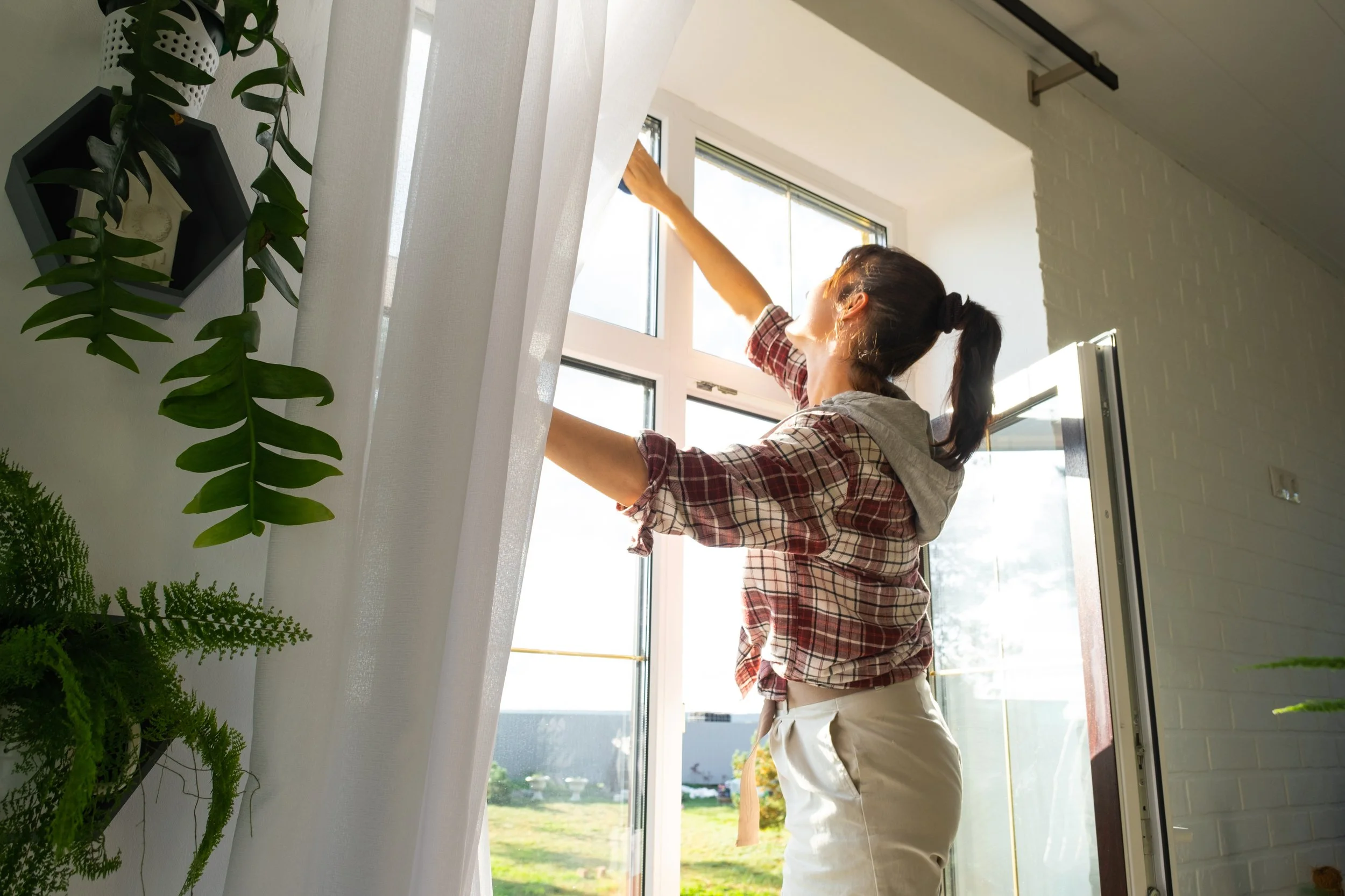 Woman cleaning interior windows and curtains during a home deep clean