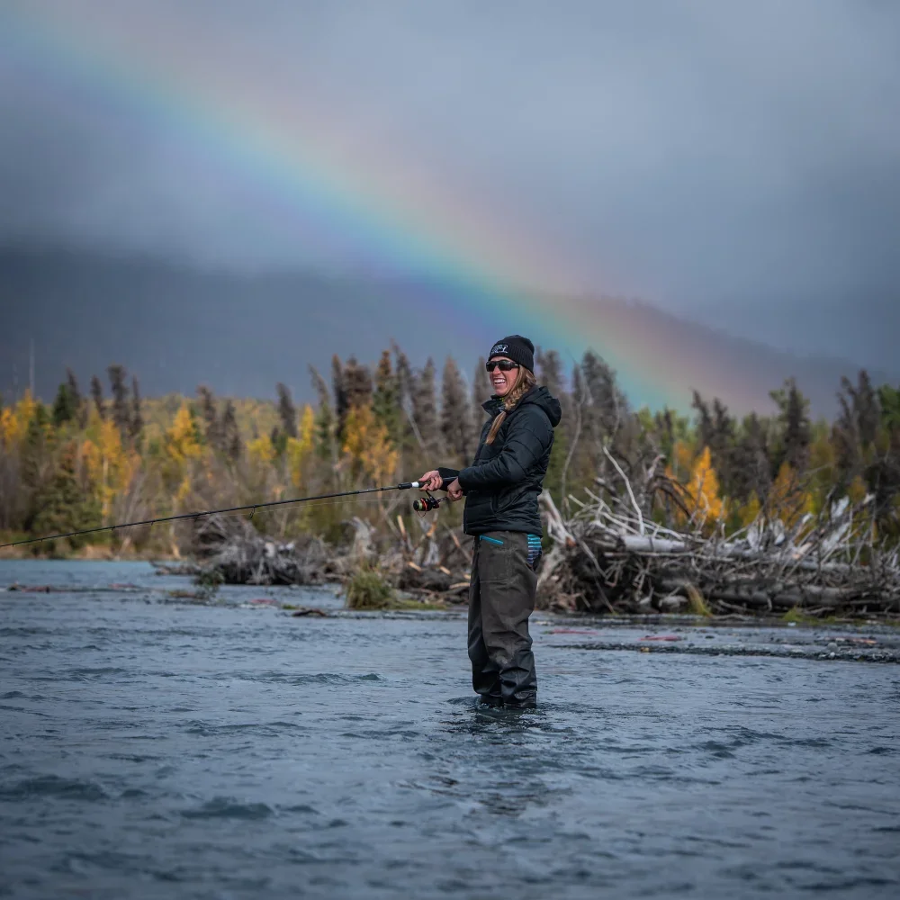 woman-fly-fishing-in-river-with-rainbow-overhead.webp