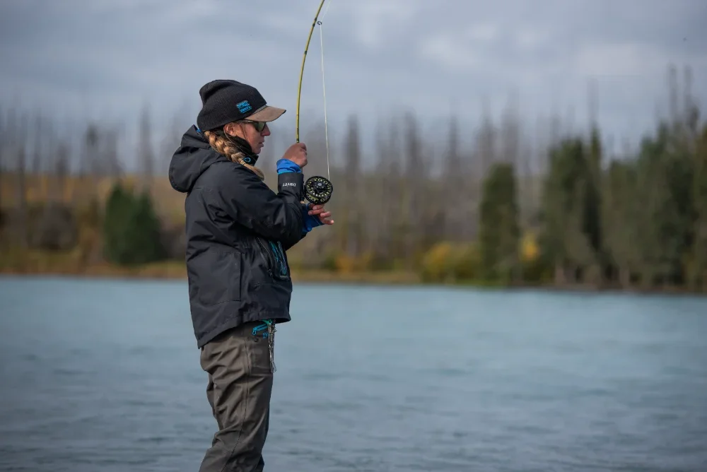 woman-fly-fishing-on-calm-river-fall-trees-background.webp
