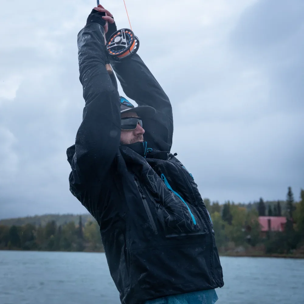 man-holding-fly-reel-overhead-on-overcast-lake.webp