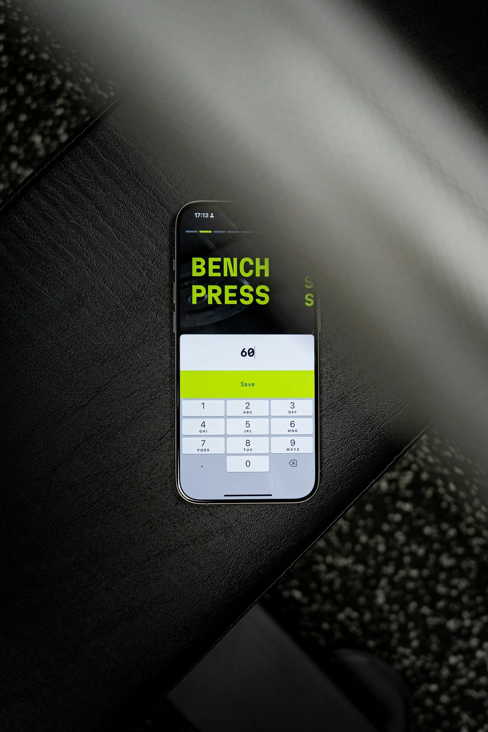 A smartphone screen displaying a calculator app with the number 69 entered, and the words 'BENCH PRESS' in bright green text over the screen.