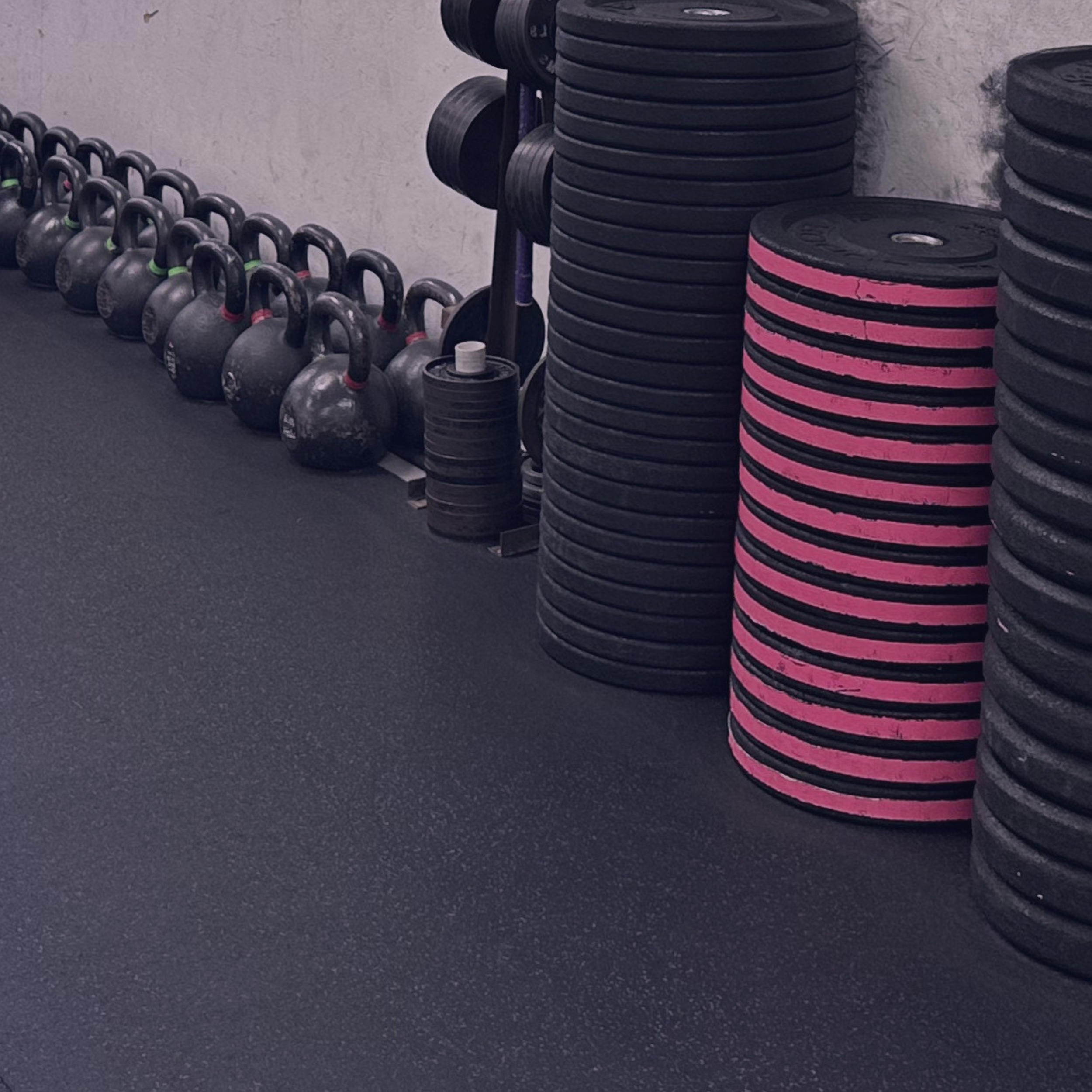 Stacked weight plates and kettlebells in a gym setting.