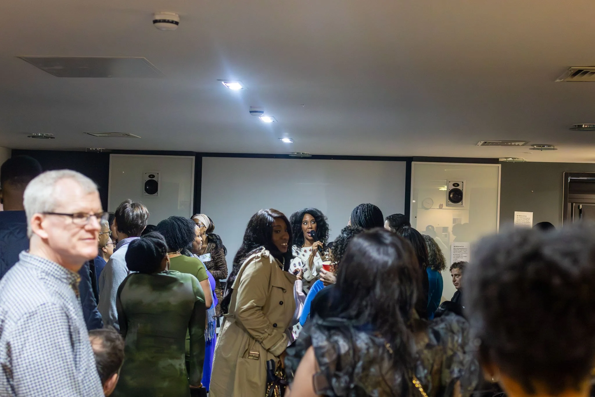 A diverse group of people gathered indoors, engaging in conversation and socializing at a singles event.