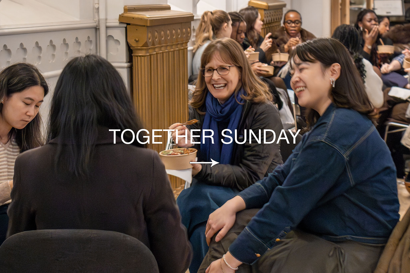 Group of people sitting together, enjoying a meal and laughing during a social gathering, with the text 'TOGETHER SUNDAY' overlaid.