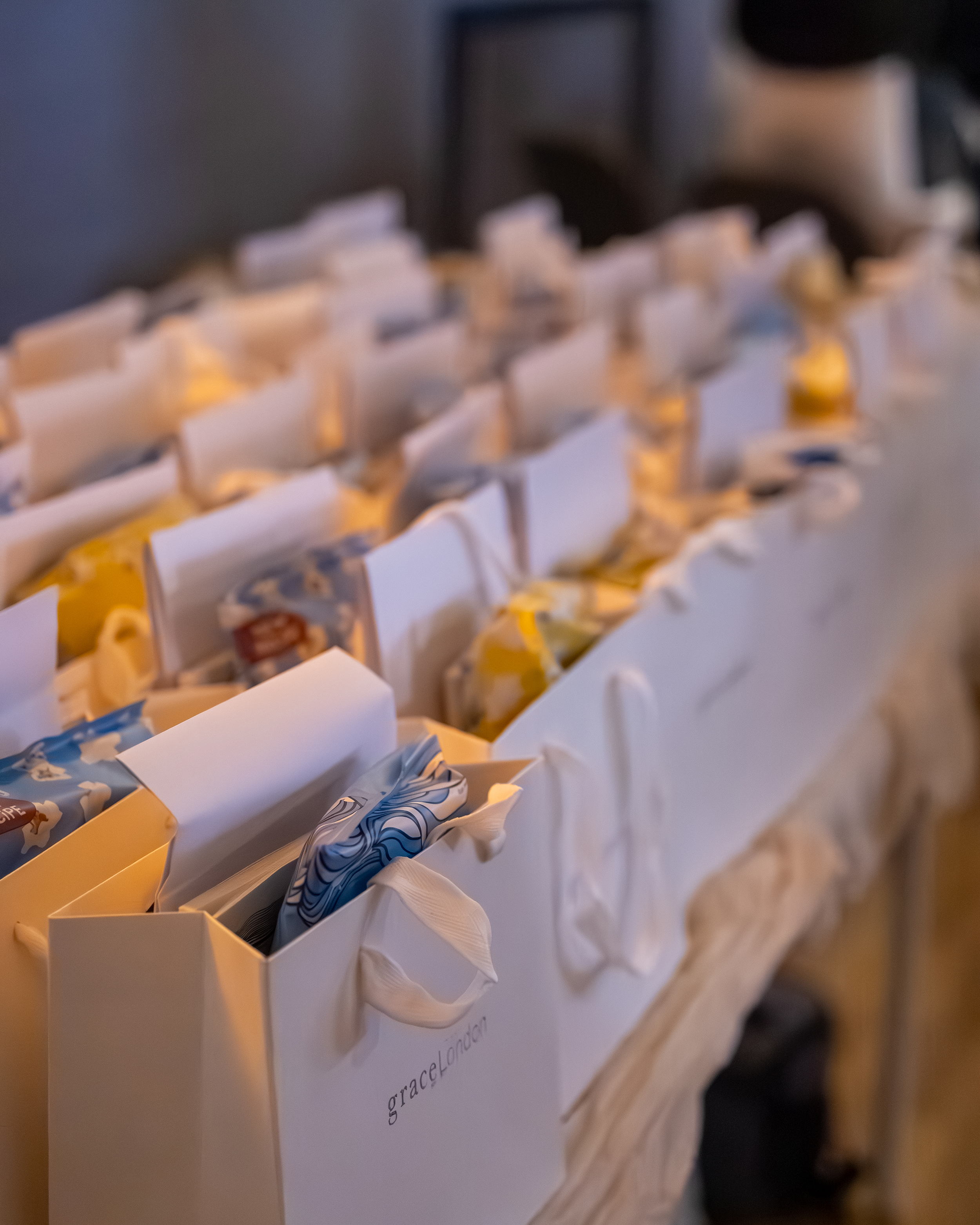 Close-up of a white box with individual compartments containing paper tissues, some tissue papers are protruding out. The background is blurred, and the box appears to be placed on a wooden surface.