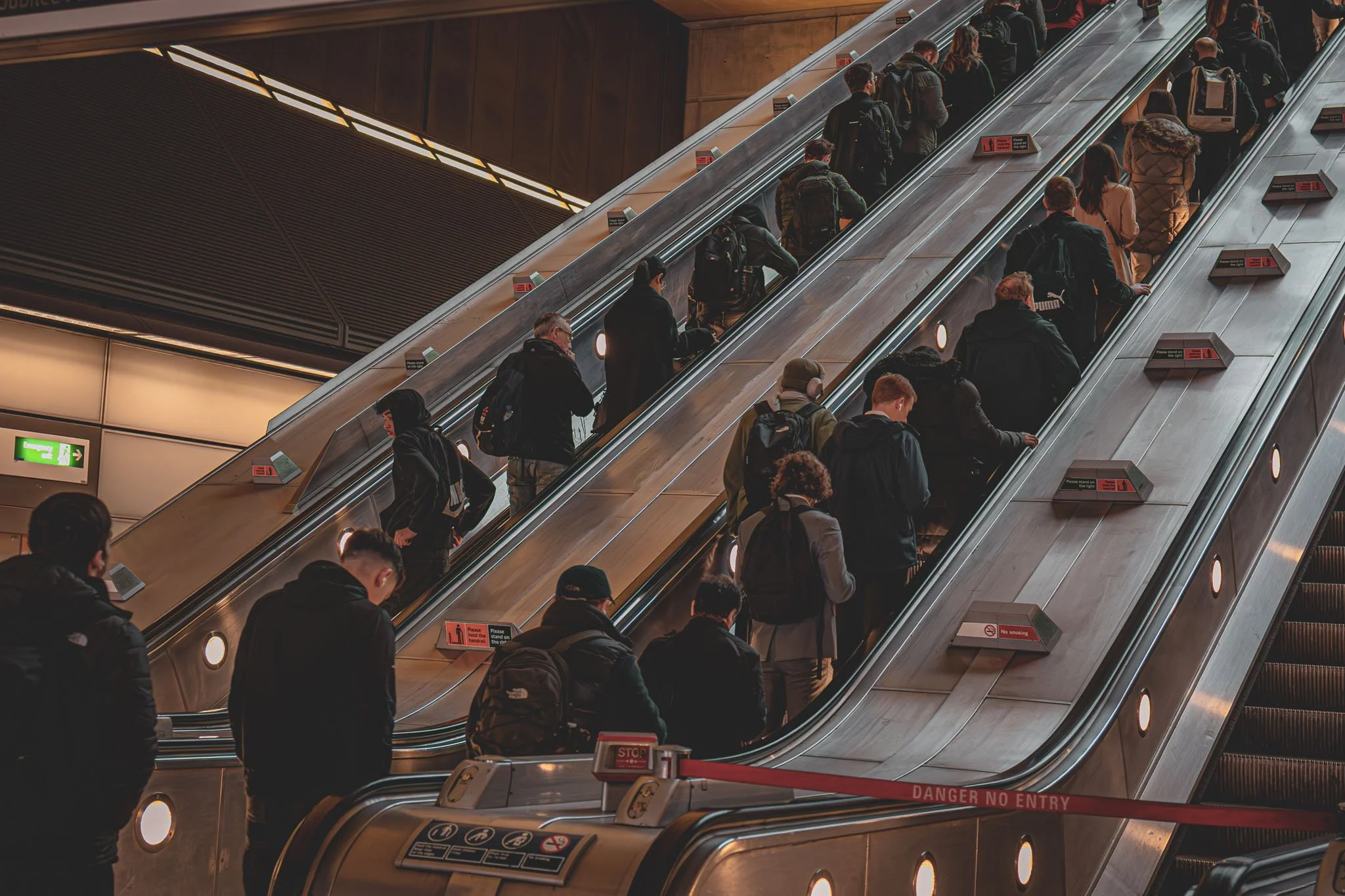 People standing in line on escalators at Canary Wharf underground station.