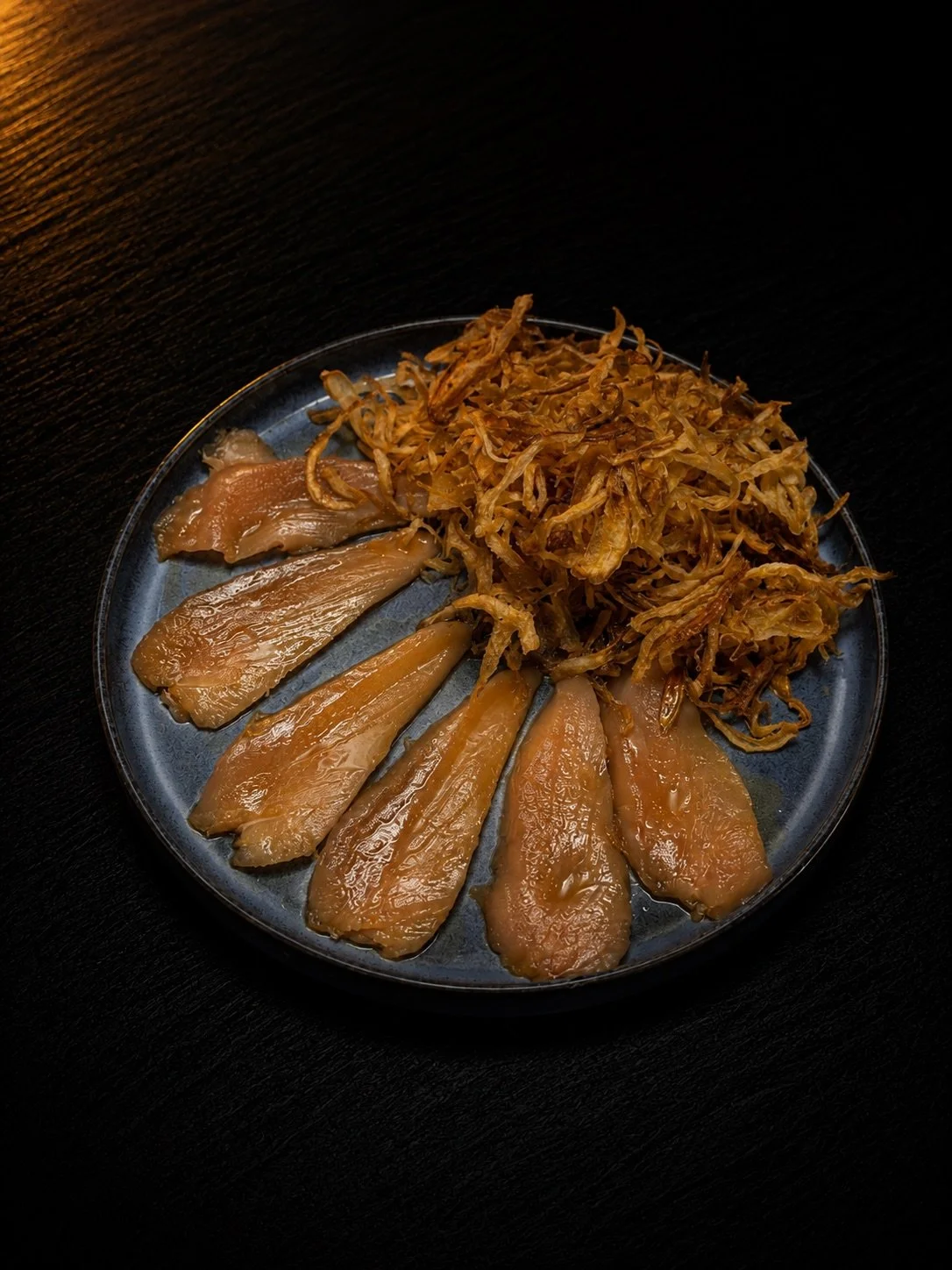 Sliced pork with shredded cooked cabbage on a dark plate.