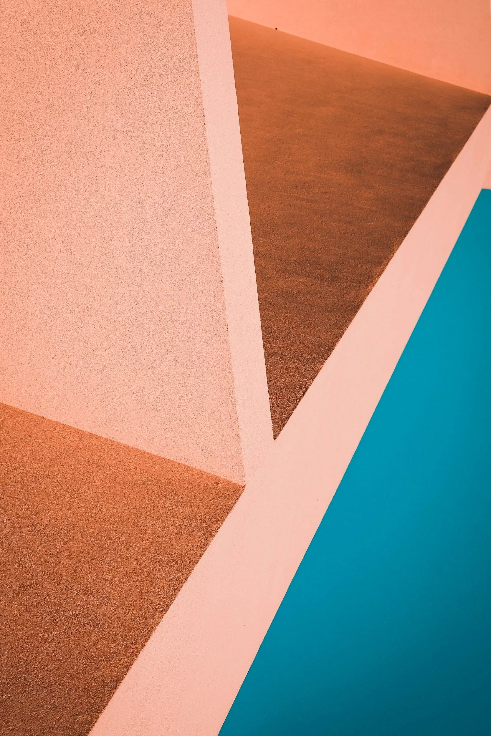 Close-up of a colorful architectural interior with pink, brown, and blue walls intersecting at angles.