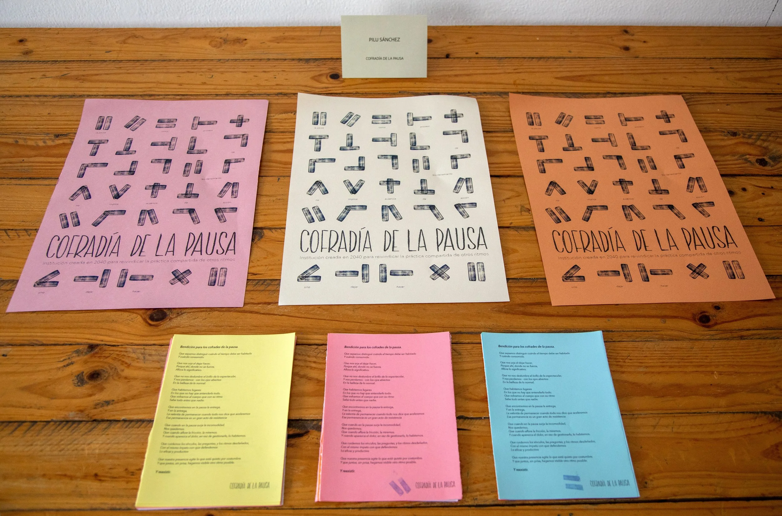 Carteles con letras y símbolos para aprender matemáticas, en colores rosa, blanco y naranja, en una mesa de madera.