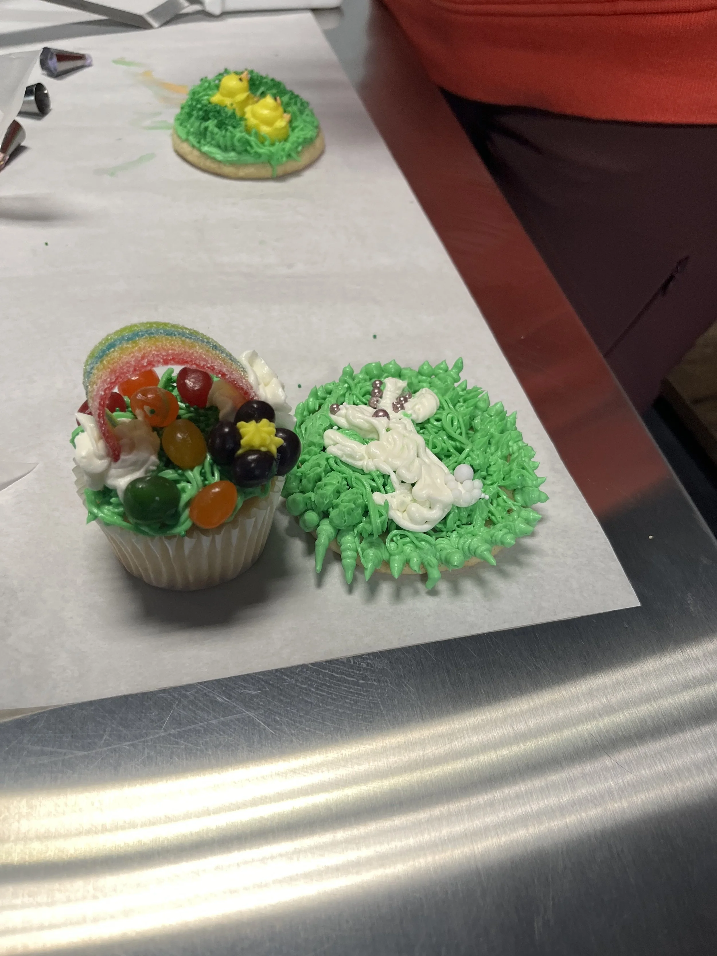 Decorated cupcakes with colorful frosting, sprinkles, and candy toppings on a parchment paper sheet.