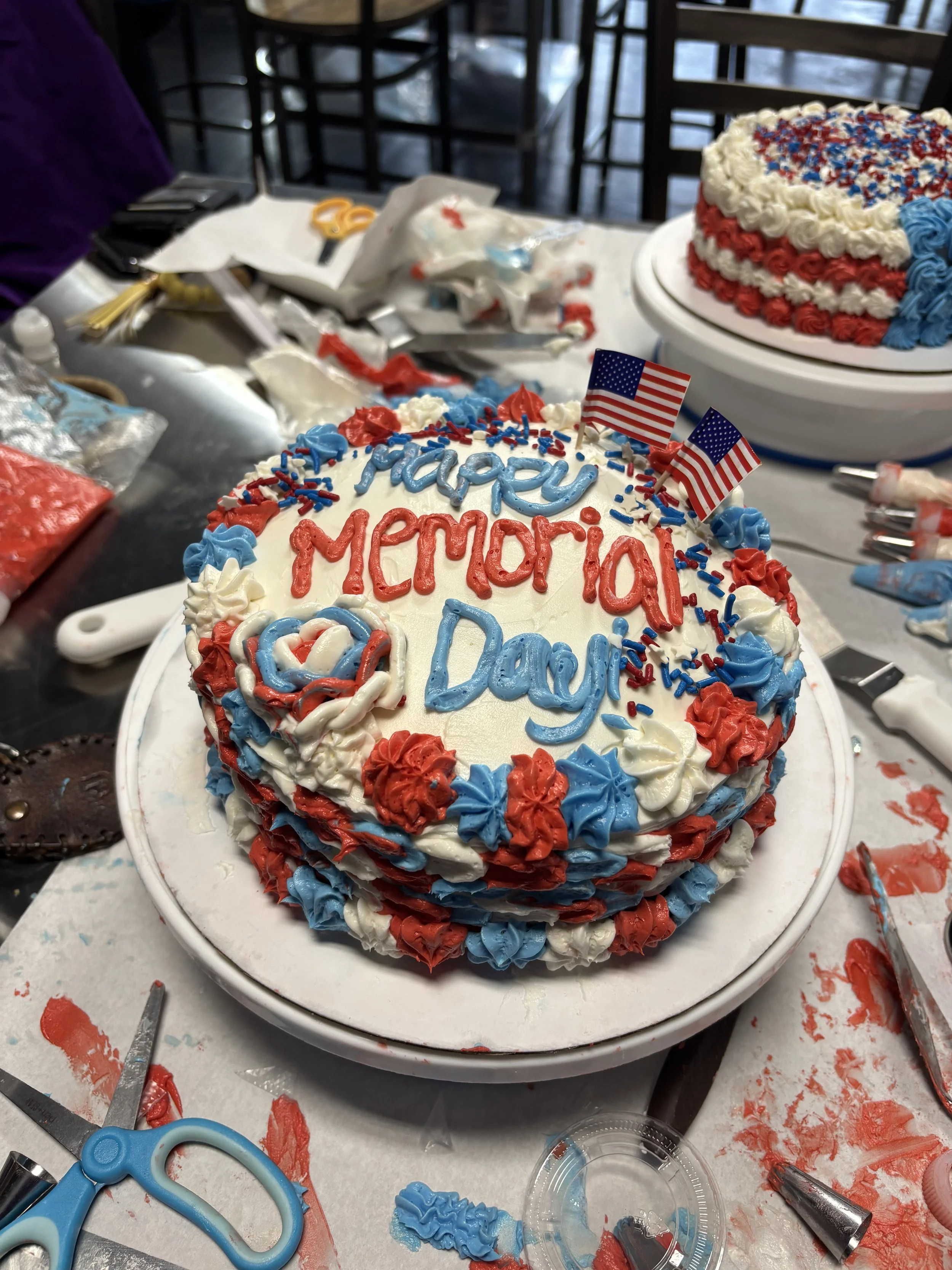 Patriotic themed cakes decorated with red, white, and blue frosting, and small American flags.