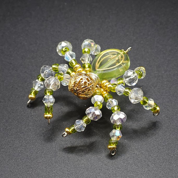 A decorative spider ornament made of beads and glass pieces on a black surface.