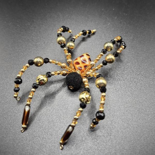 A beaded spider made with a central bead with a dotted pattern and velvet beads for body.