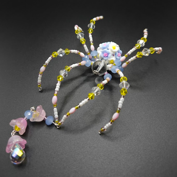 Beaded craft resembling spider with colorful beads, arranged on a black surface.