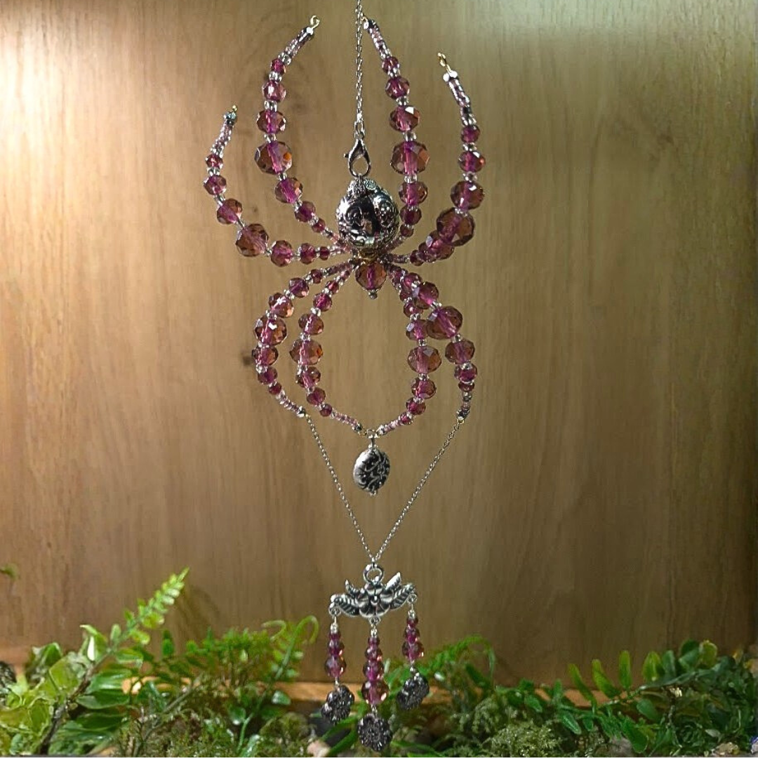 Jewelry necklace and earrings with pink beads and silver details hanging against a wooden background.