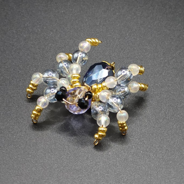 Beaded spider with black, gold, pearl, and faceted dark gray beads.