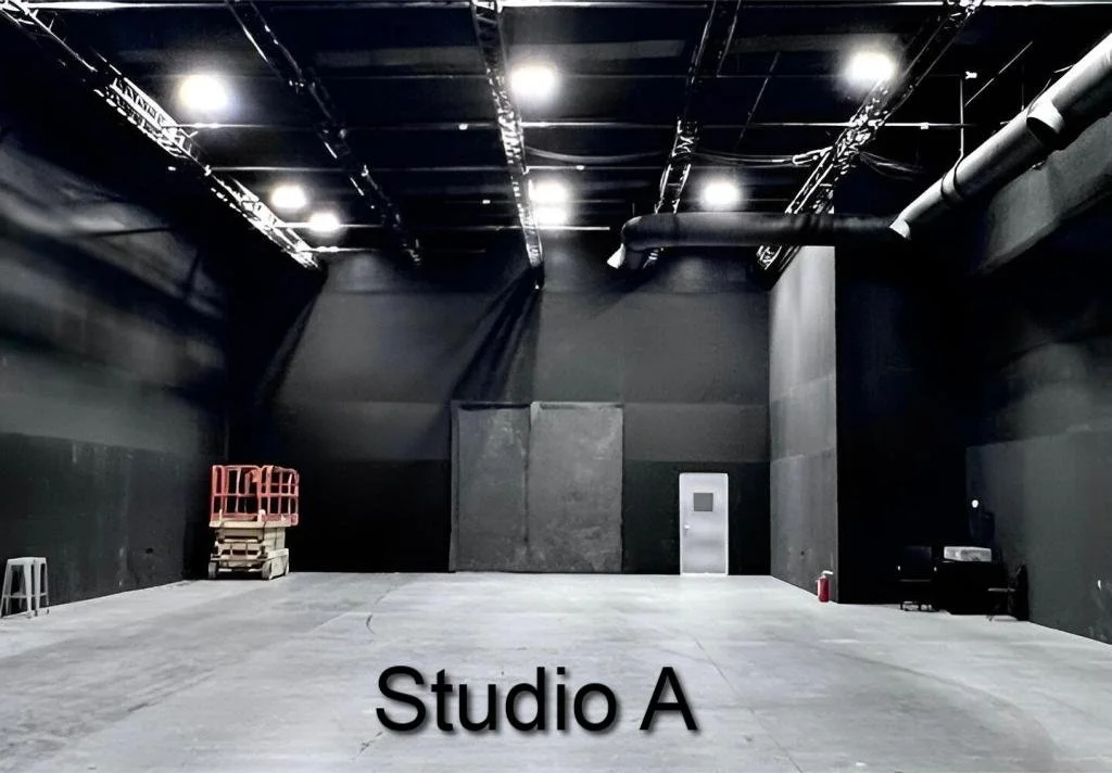 Large, empty black-walled studio space labeled 'Studio A' with equipment, a scissor lift, and a fire extinguisher.