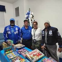 Four brothers standing behind a table with books and toys, smiling at the camera.