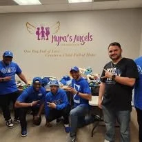 Fraternity brothers in Greek blue and white paraphernalia posing for a photo after a community service event.