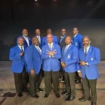 Fraternity brothers in matching blue fraternity blazers posing for a photo after a day of worship at a local church.