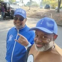 Fraternity brothers wearing blue paraphernalia while posing outdoors.