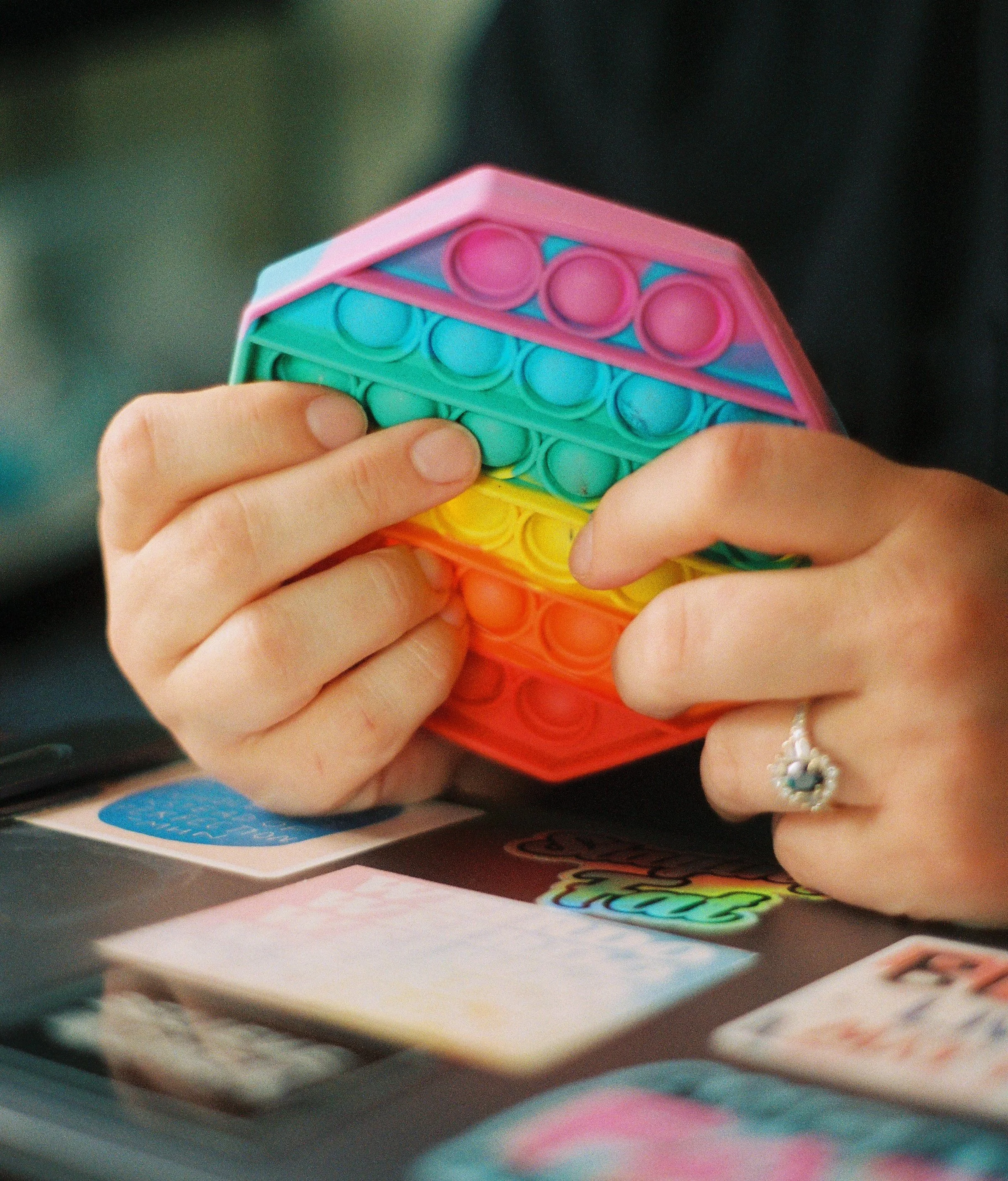 Close of up hands holding rainbow colored pop it fidget
