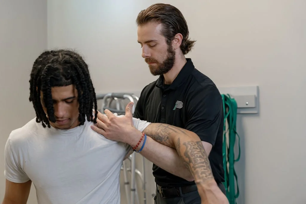 Physical therapist assisting a man with shoulder mobility exercises in a clinic