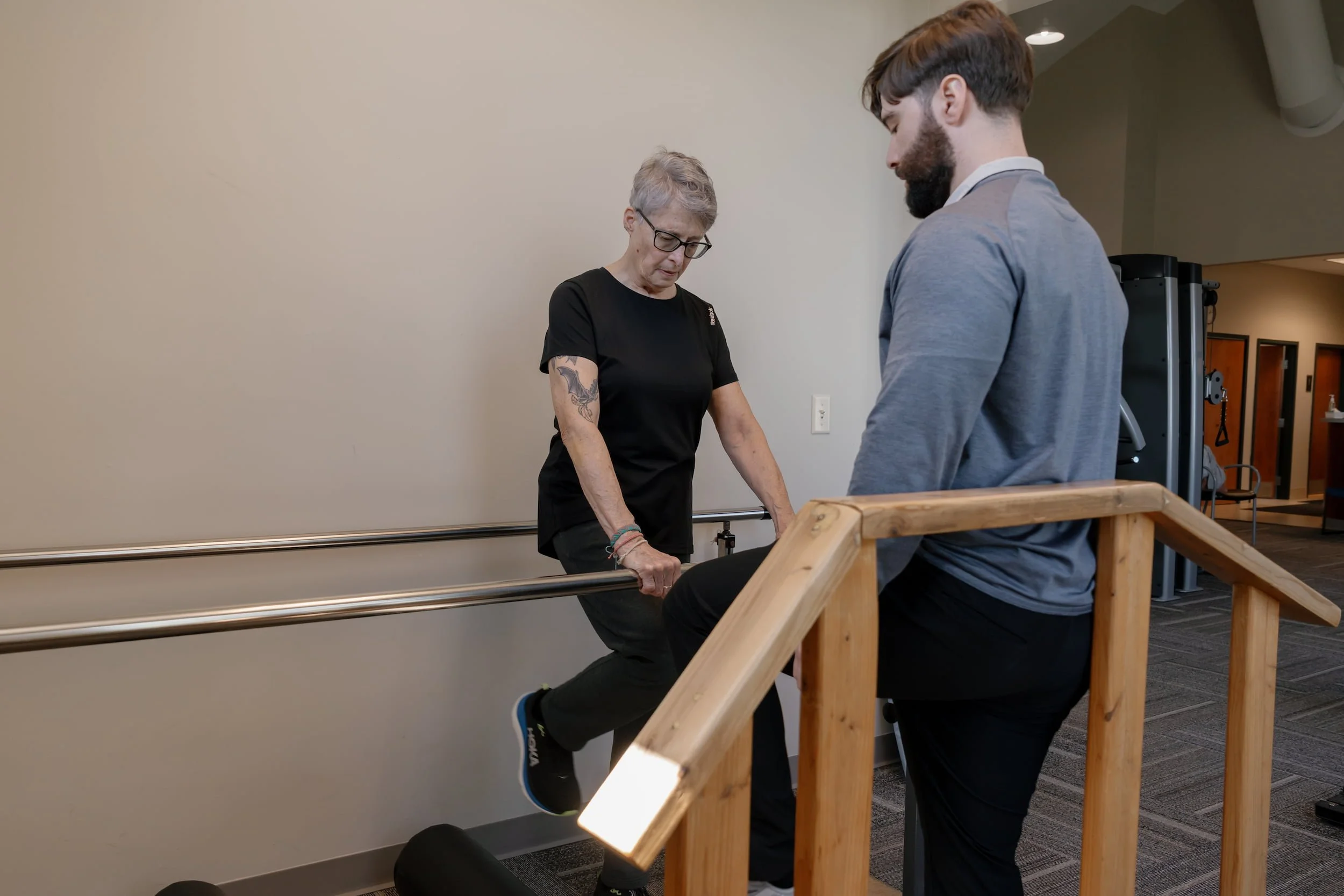 Older woman working with physical therapist on balance bars