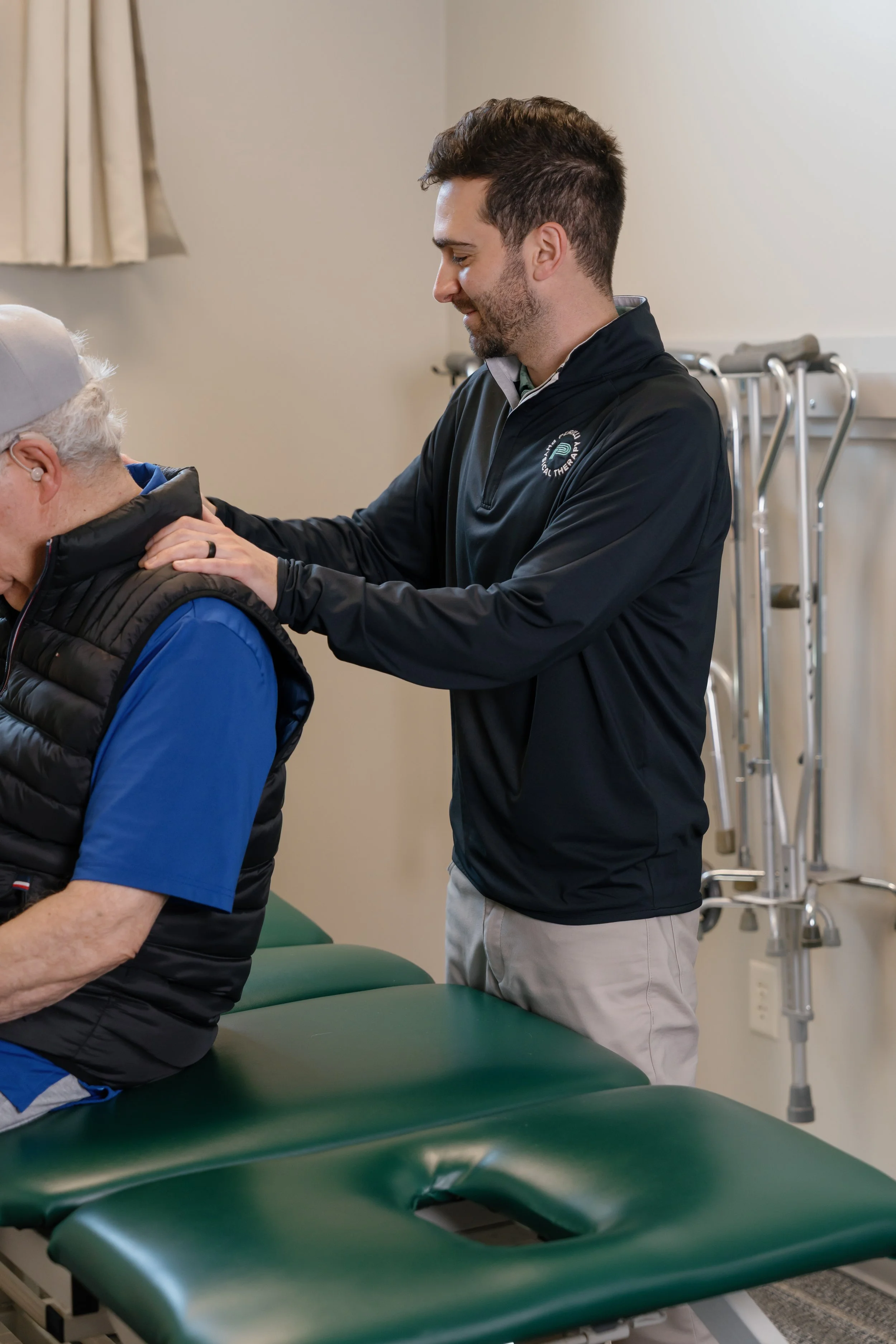 Physical therapist assisting an older patient on a treatment table in a rehabilitation clinic