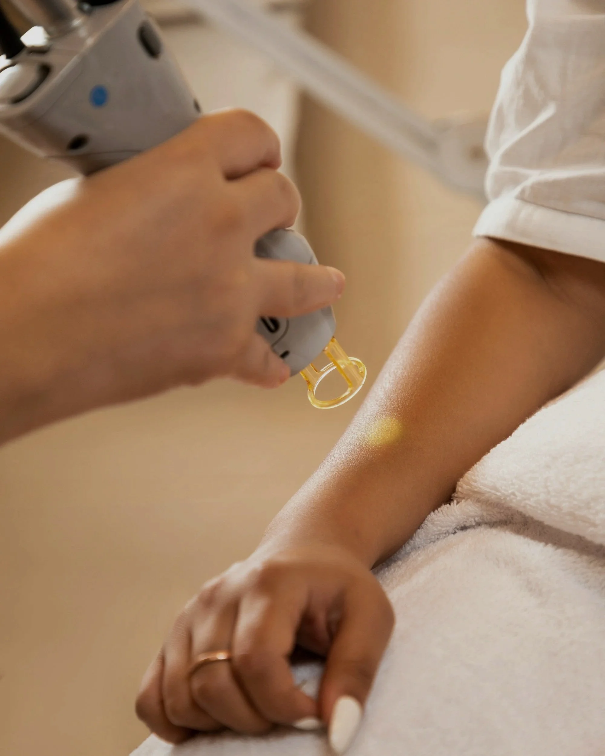 Close-up of a person holding a syringe, preparing to give an injection into their arm, which is resting on a soft, white surface.