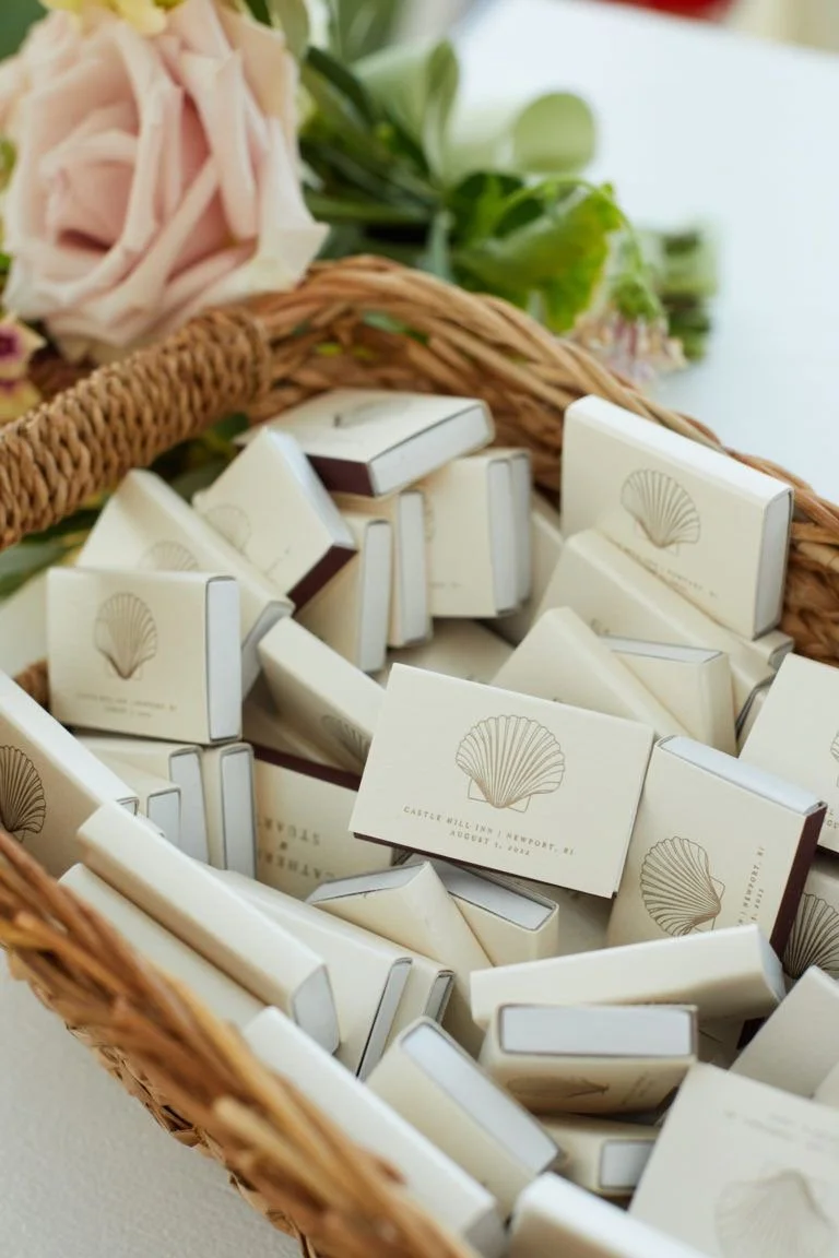 Small soap bars in a wicker basket, with a pink flower and green leaves in the background.
