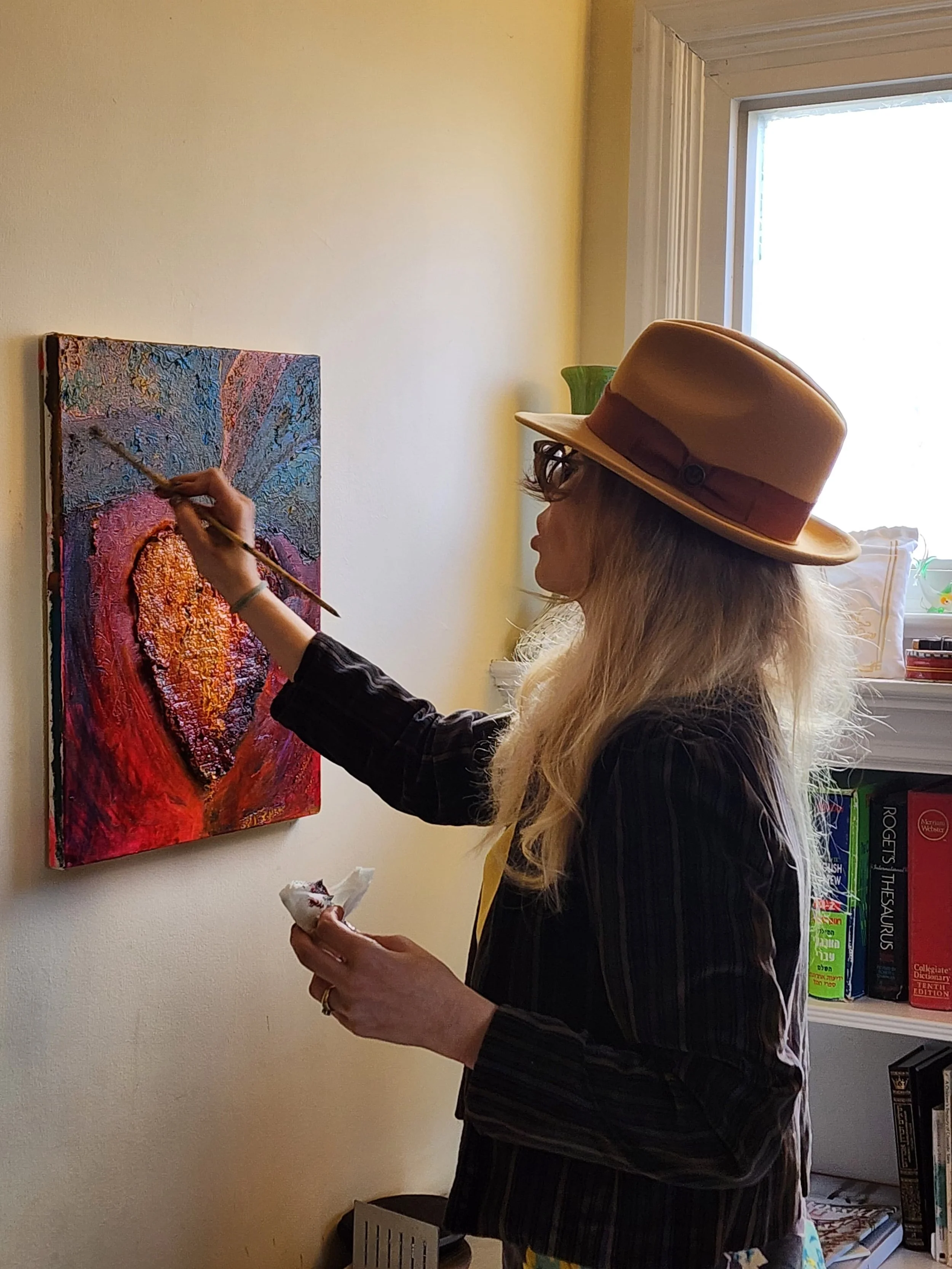 Tamara Eve Byrnes painting a colorful abstract on a canvas mounted on the wall.