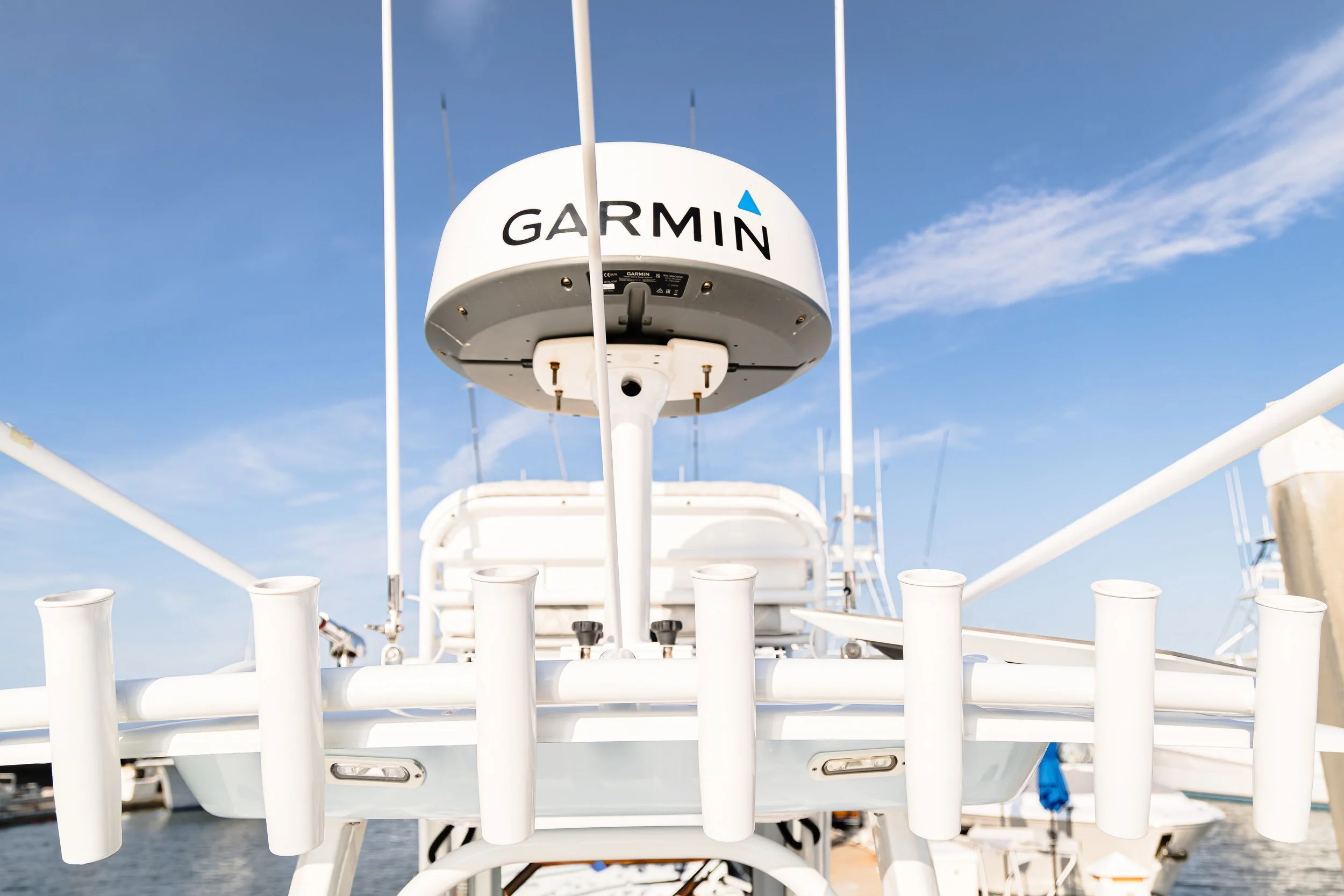 Close-up of a Garmin radar antenna mounted on a boat with a blue sky and some clouds in the background.