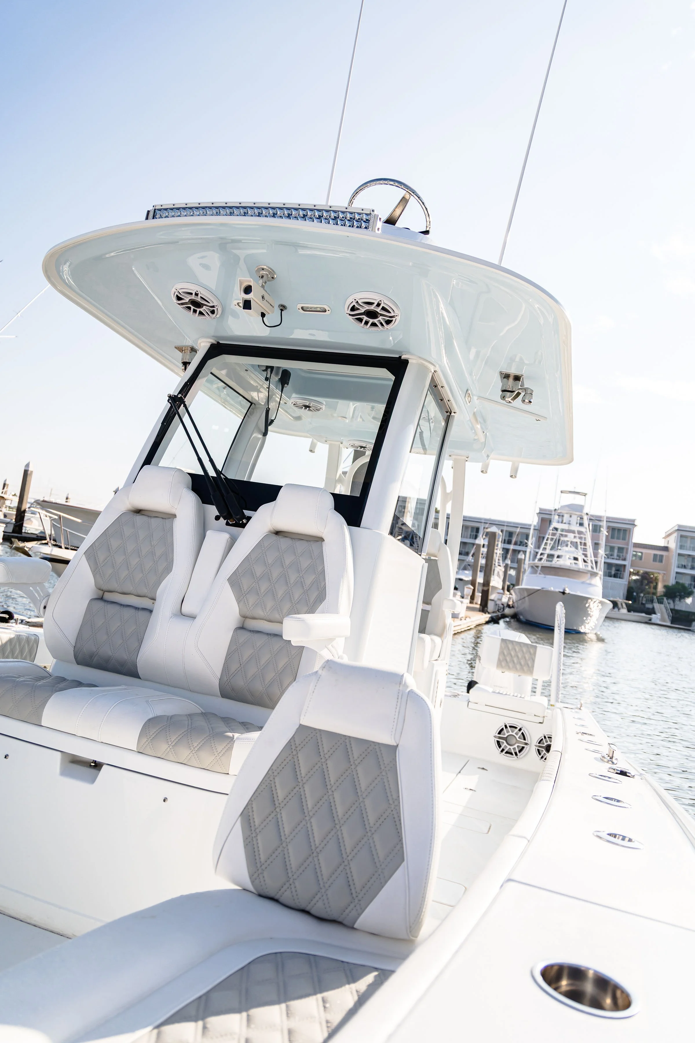 A luxury white yacht docked at a marina with seating and speakers visible.