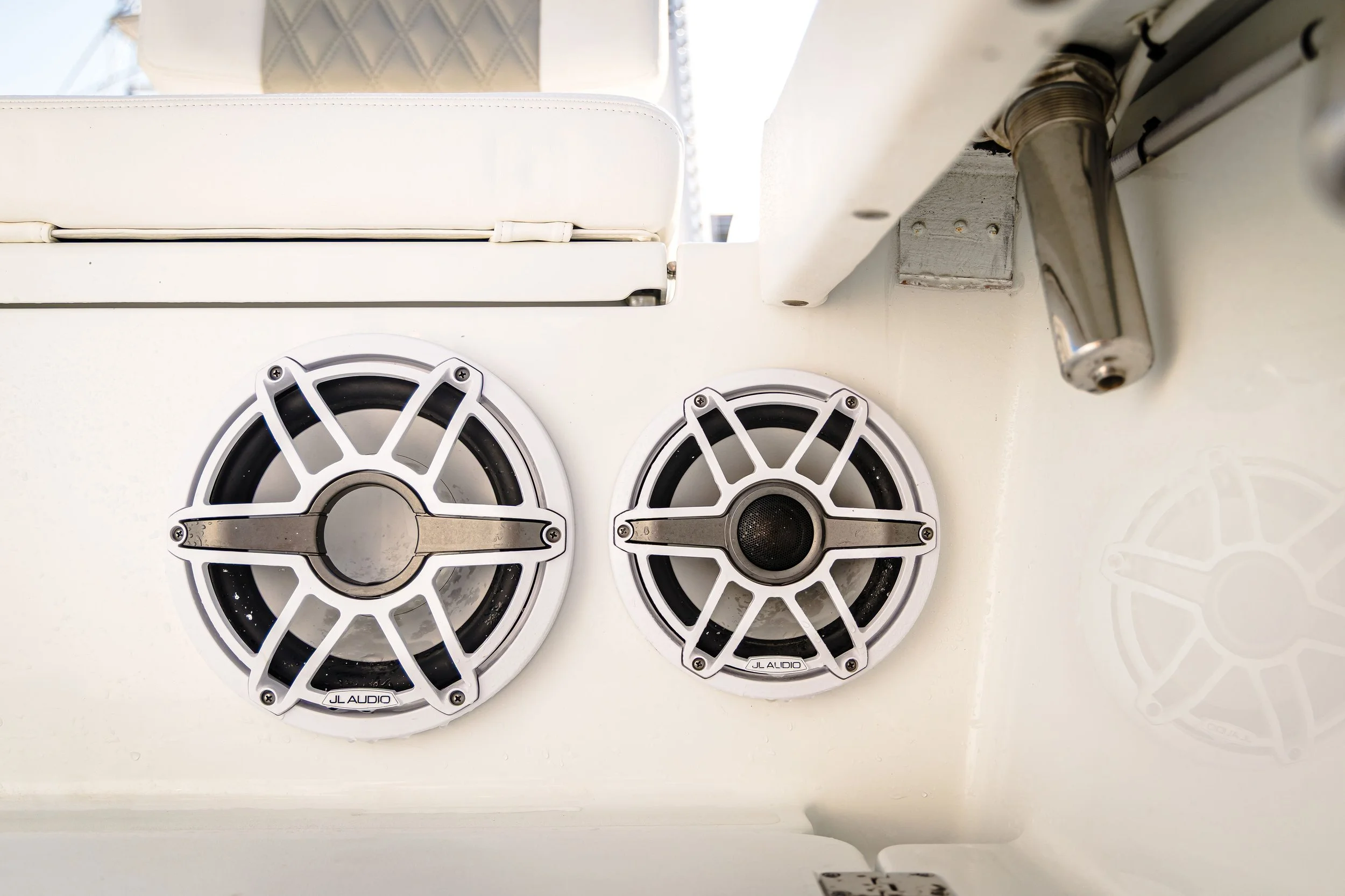 Two JL Audio boat speakers installed on a white surface.