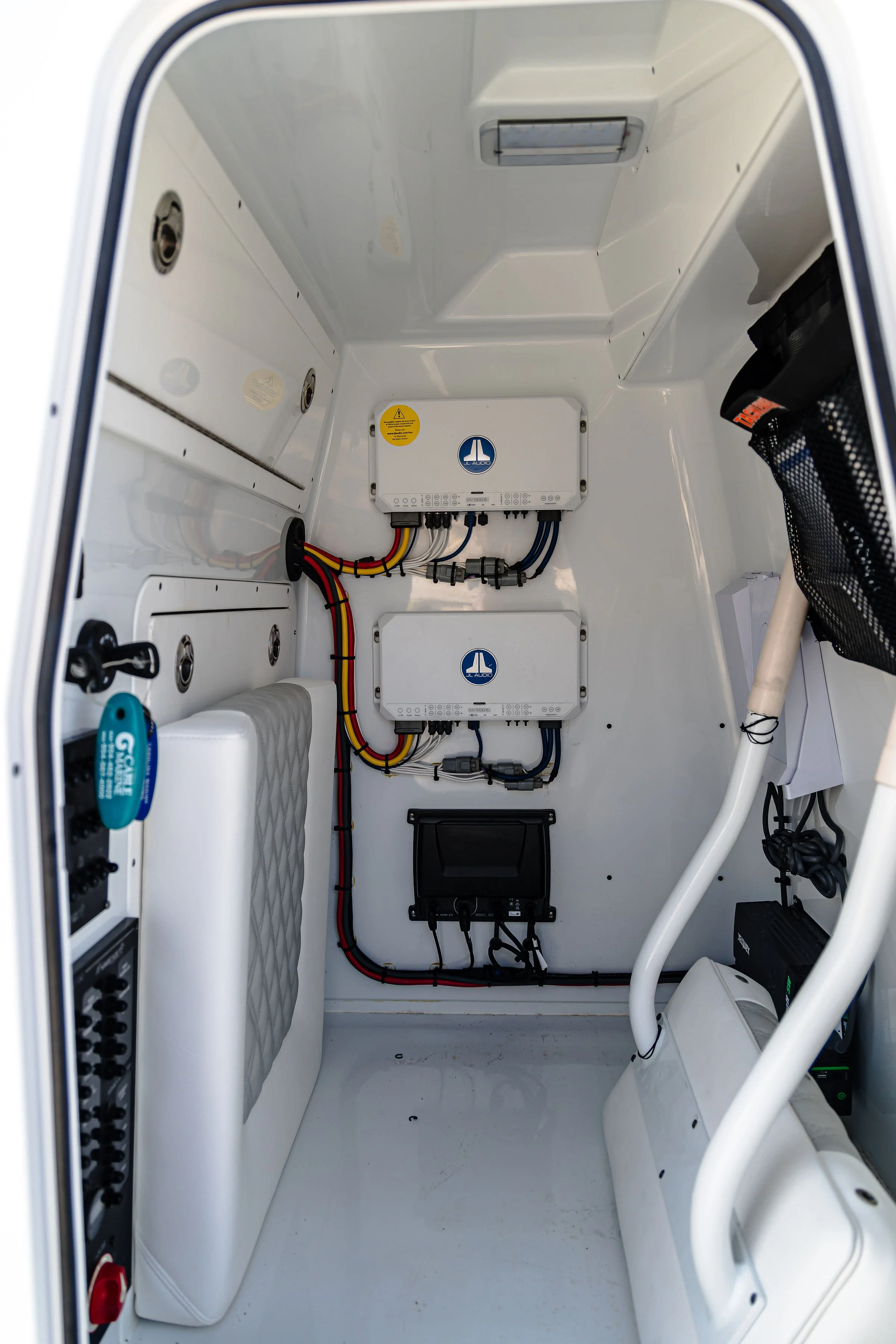 The interior of a small, white, enclosed electrical or communication cabinet with various electronic components, wires, and panels.