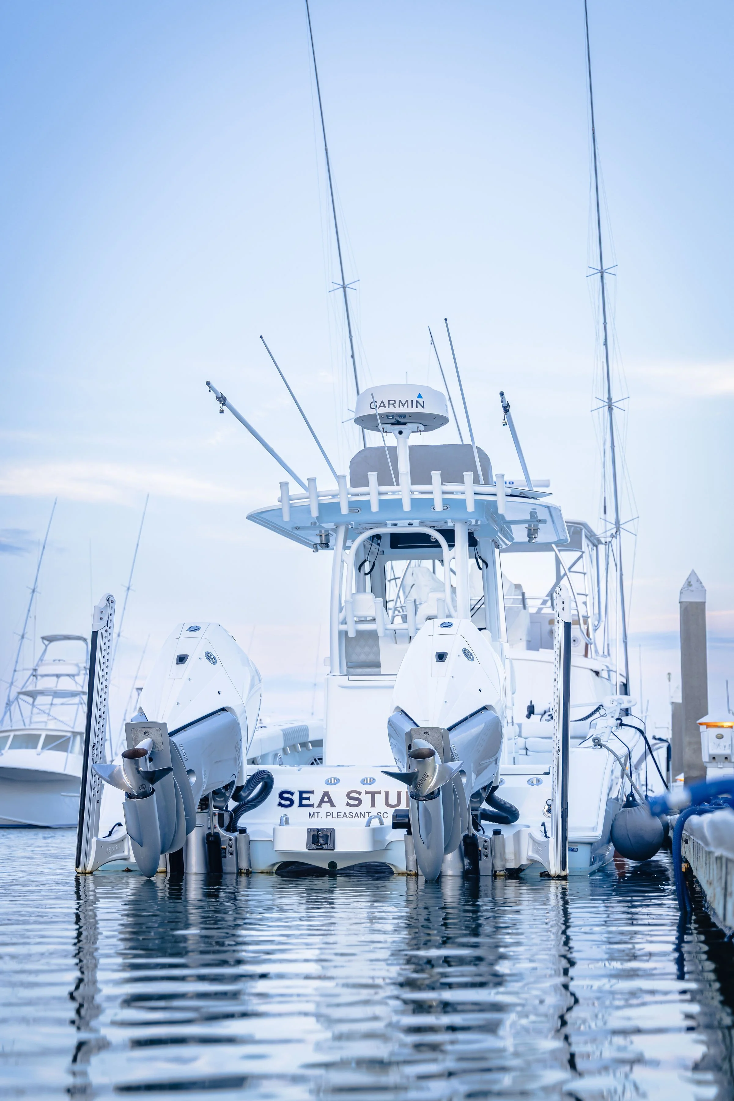 White motor yacht docked at a marina, with various antennas and equipment on the top, under a blue sky with some clouds.