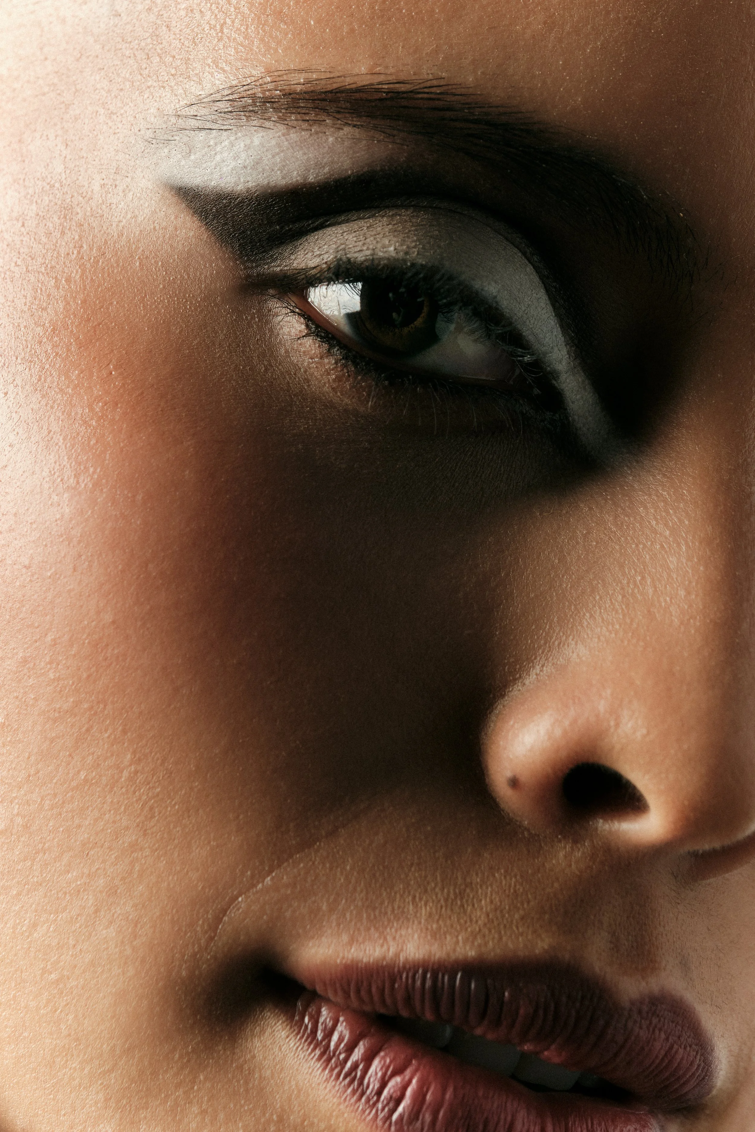 Primer plano del rostro de una persona con maquillaje de ojos y labios.