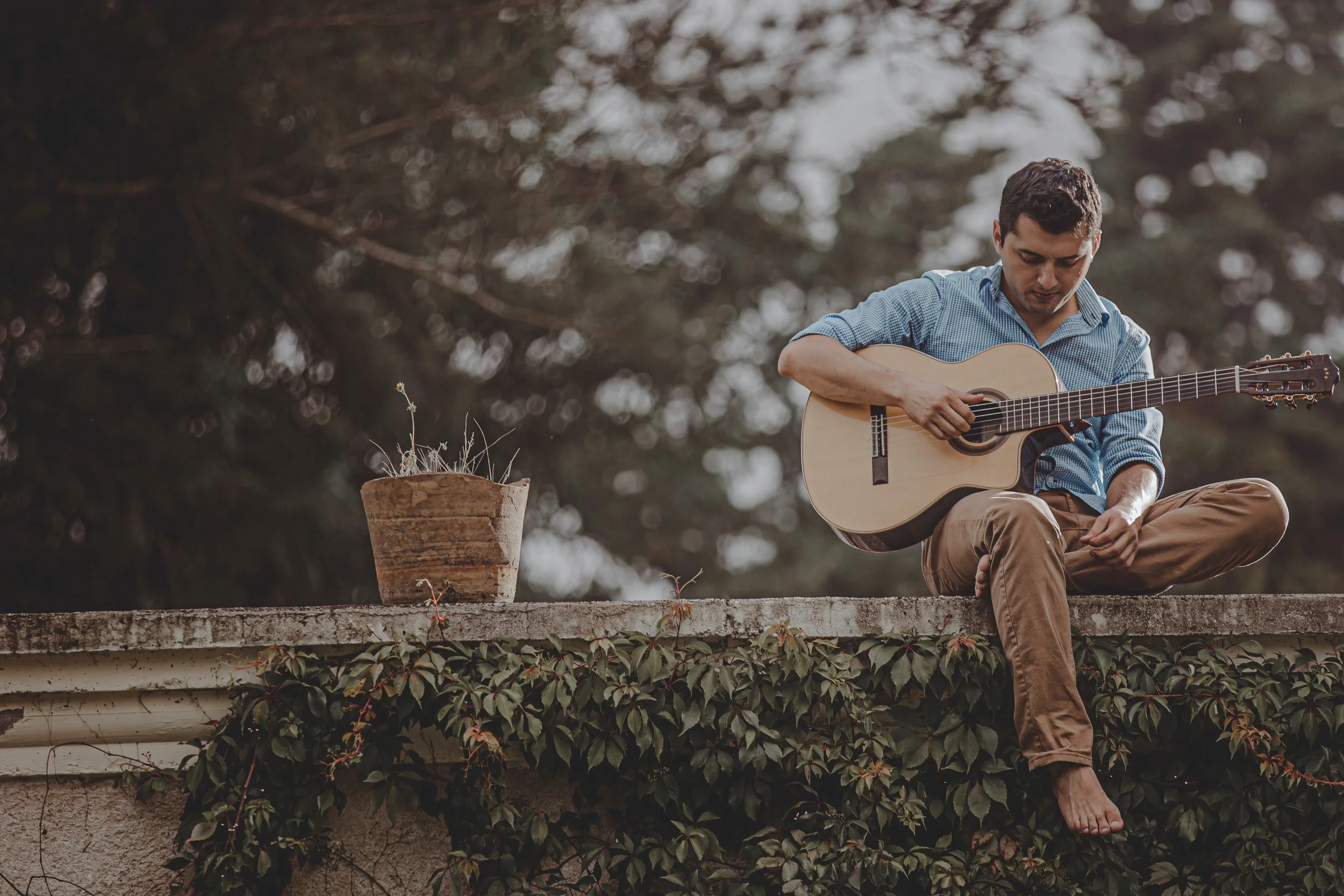 Sergio Zepeda, Guitarrista. Un hombre sentado en un alféizar con una guitarra, tocando serenamente. Flamenco, Jazz, Guitarra acústica. Música para eventos Guatemala