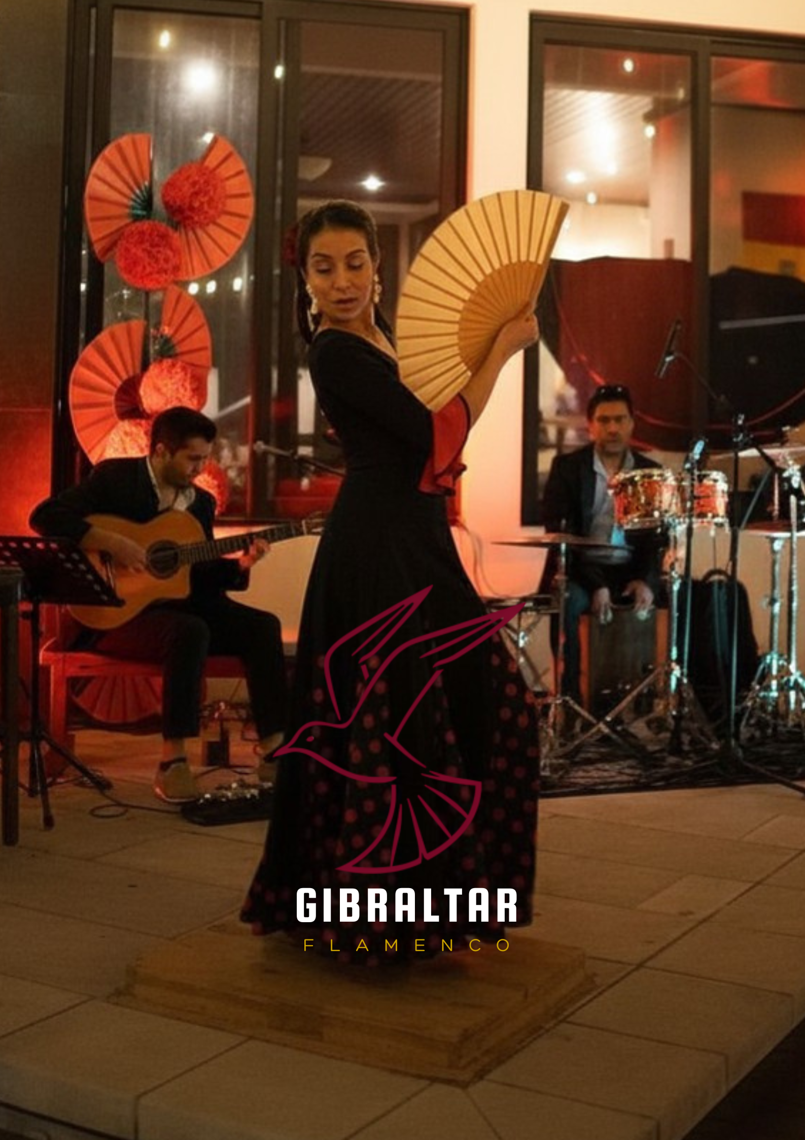 Mujer bailando flamenco con abanico en manos en un escenario, Guitarra flamenca, decoración de abanicos en la pared, ambiente cálido y elegante. Gaviota en Gibraltar. Musica para eventos Guatemala