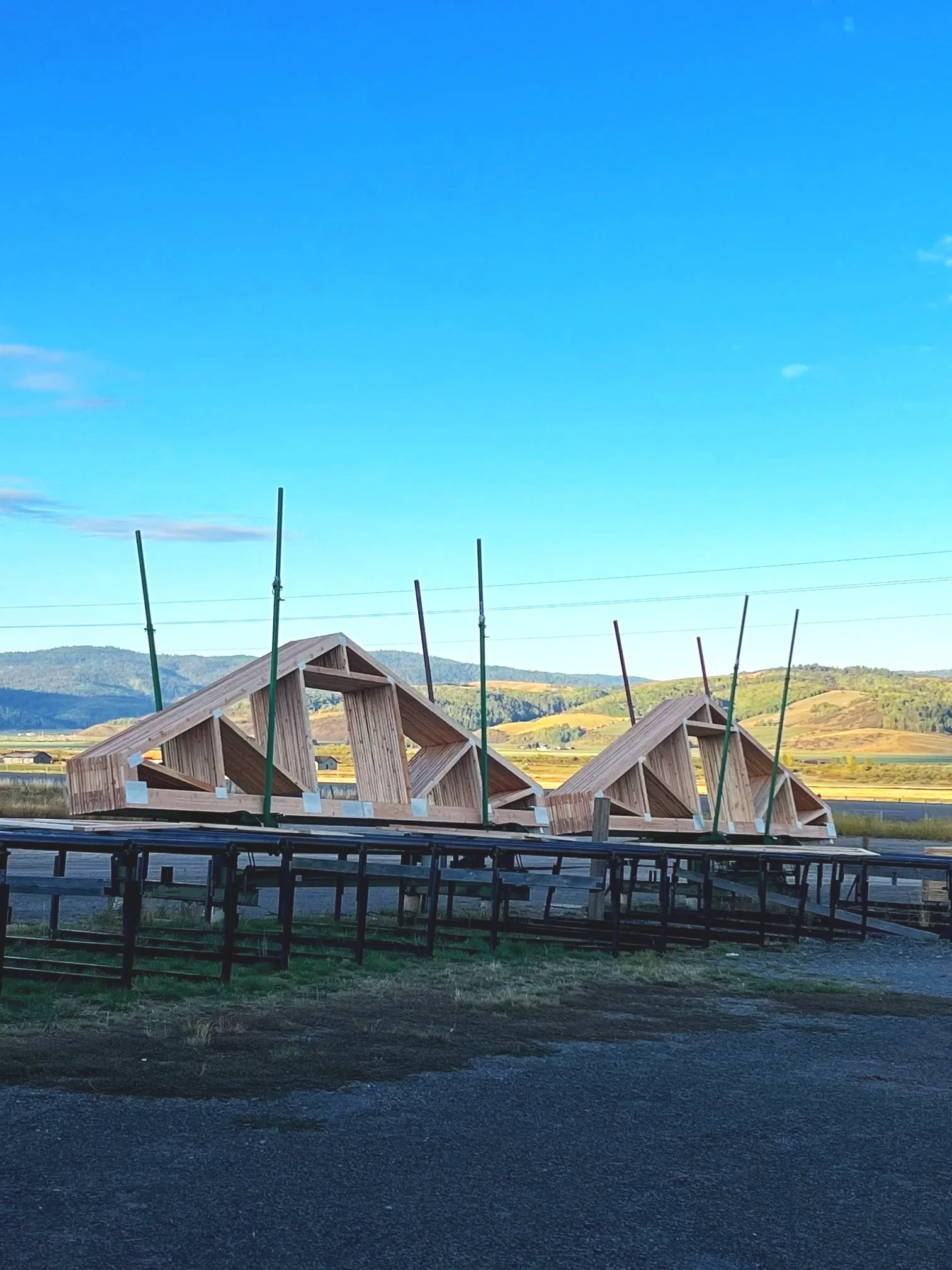 Wooden roof trusses situated in rural wyoming with rolling hills and a blue sky.
