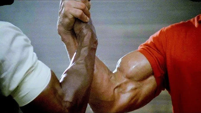 Close-up of two muscular arms engaged in an arm wrestling match.