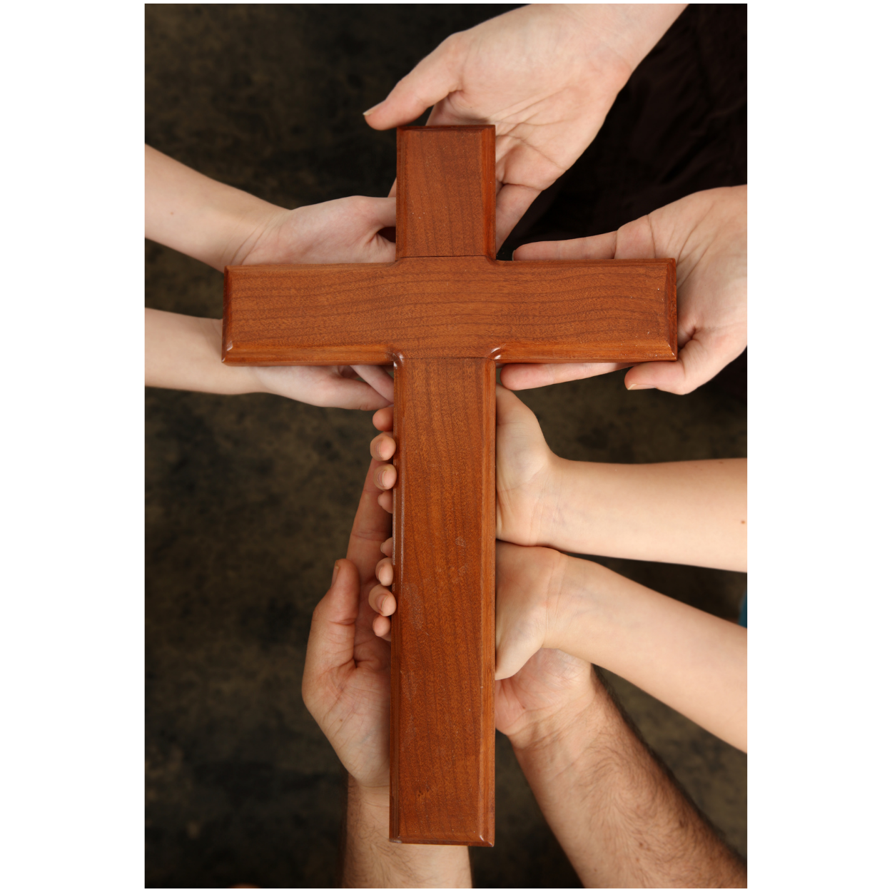 Multiple hands of different ages holding a wooden cross together.