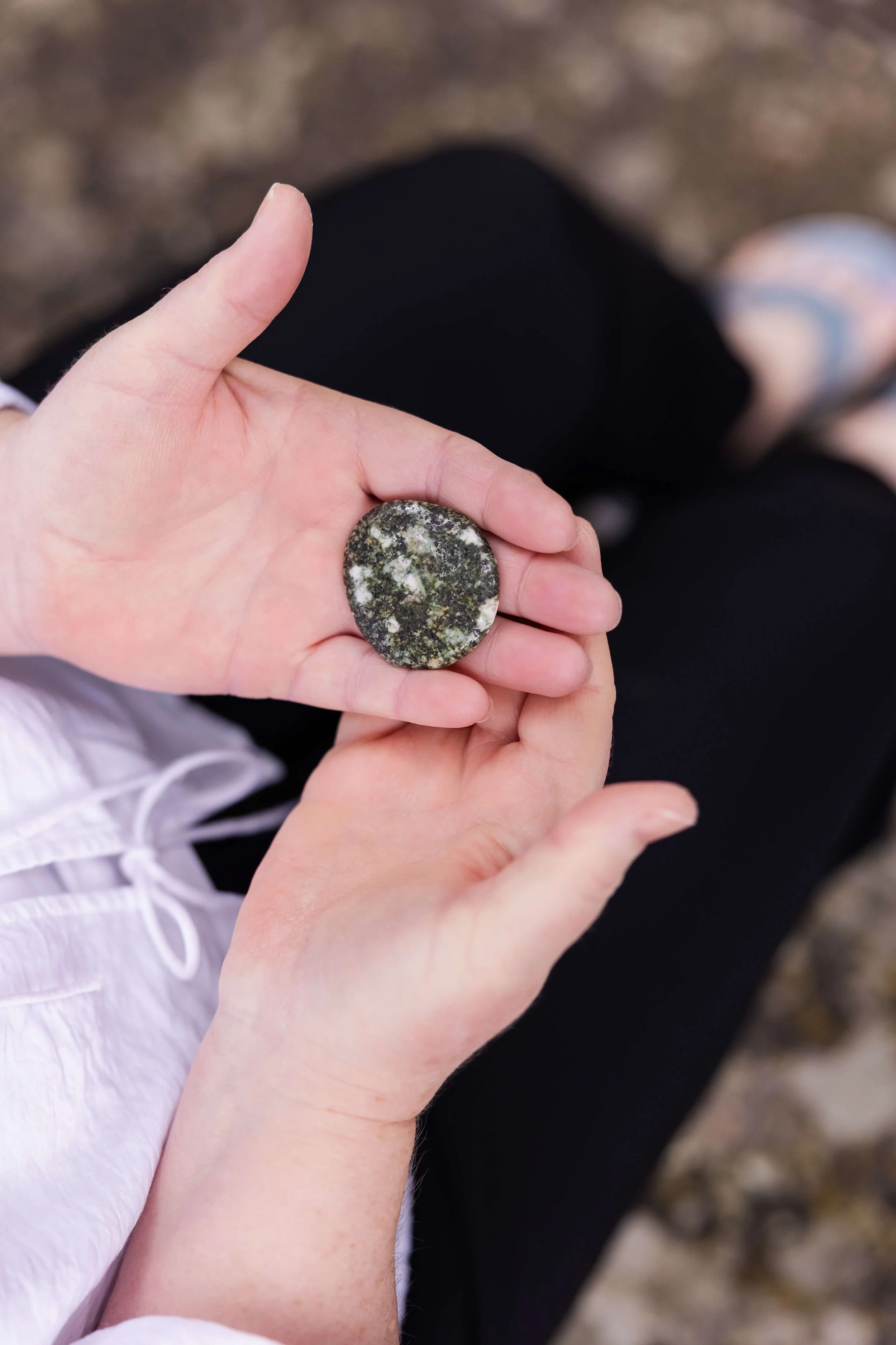 A person holding a smooth, rounded stone with a mottled gray and white pattern at a cabin retreat
